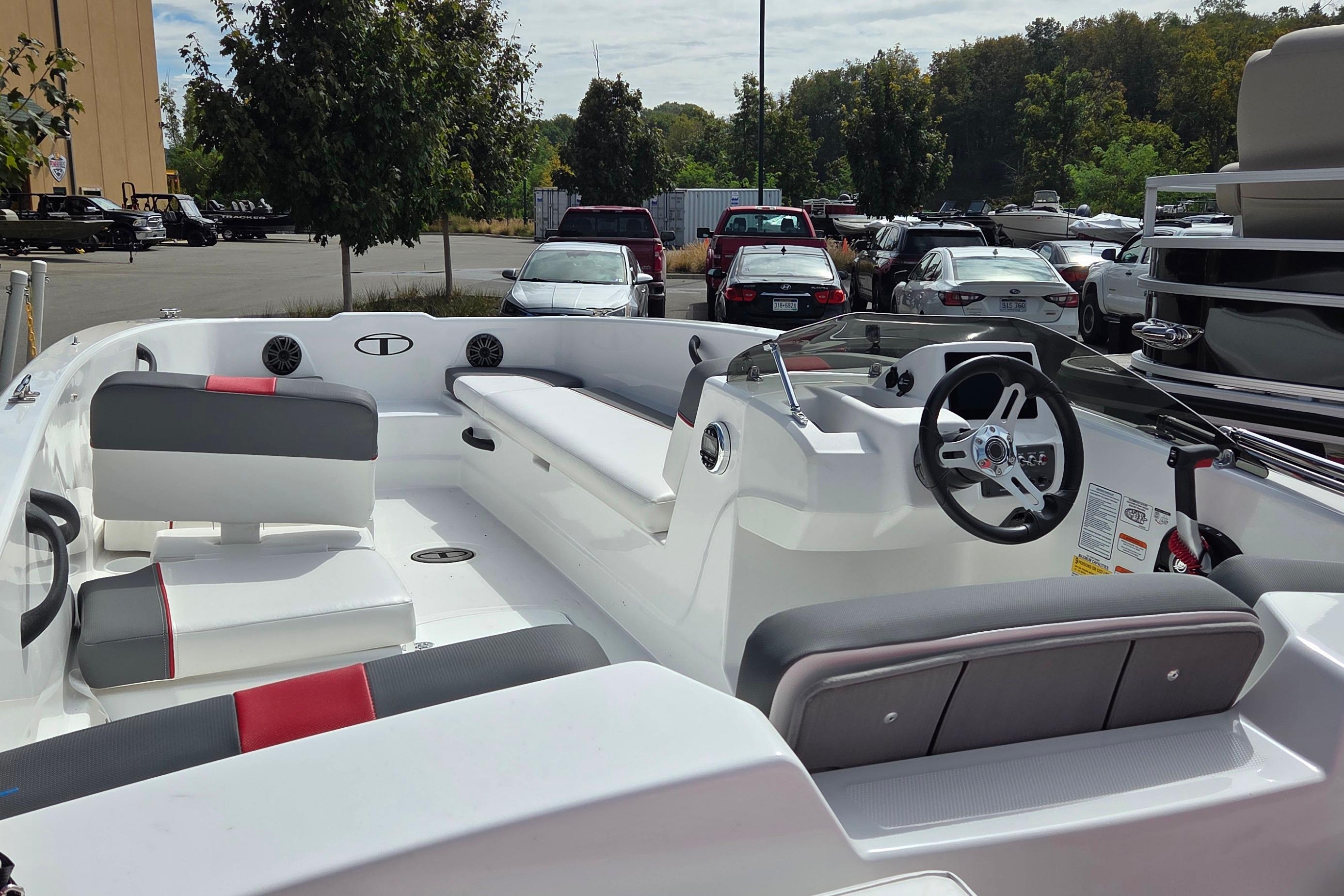 2026 Tahoe T18 boat interior with seating and steering wheel in a parking lot setting.