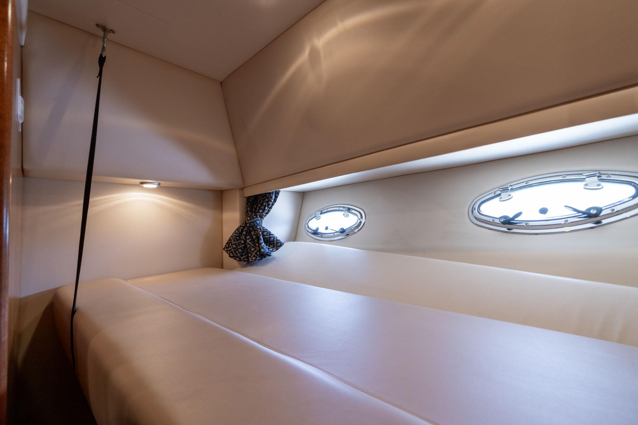 2003 Meridian 490 Pilothouse cabin interior with portholes and cozy bedding.