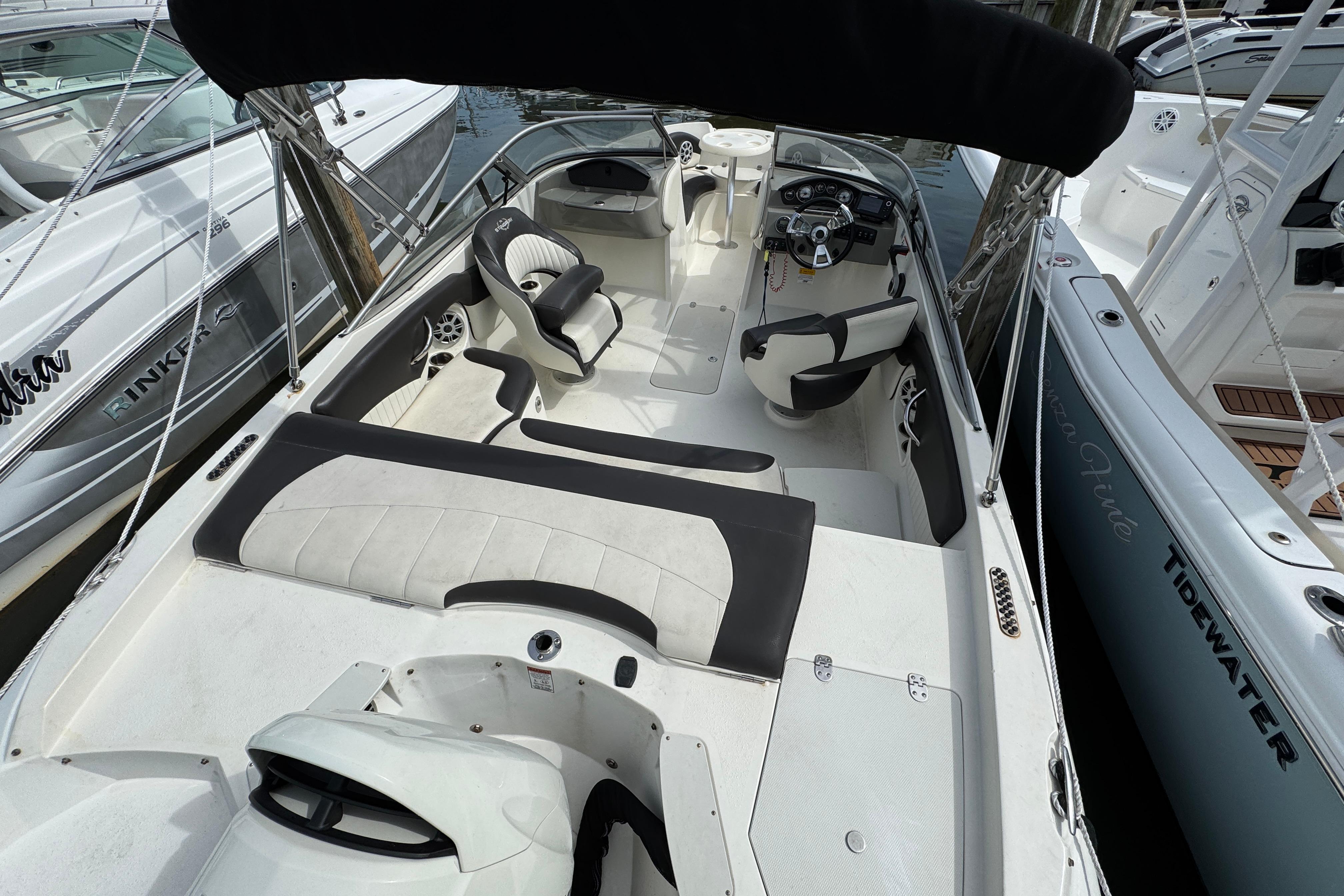 2018 Stingray 204 LR boat interior with seating and steering wheel, docked among other boats.