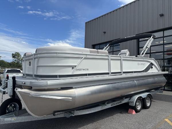 2025 Godfrey SWEETWATER 2286 SFL pontoon boat on trailer, parked outside a building.