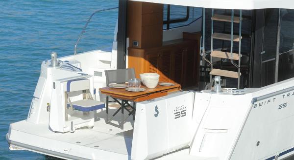 2021 Beneteau Swift Trawler 35 with outdoor deck and table on water.