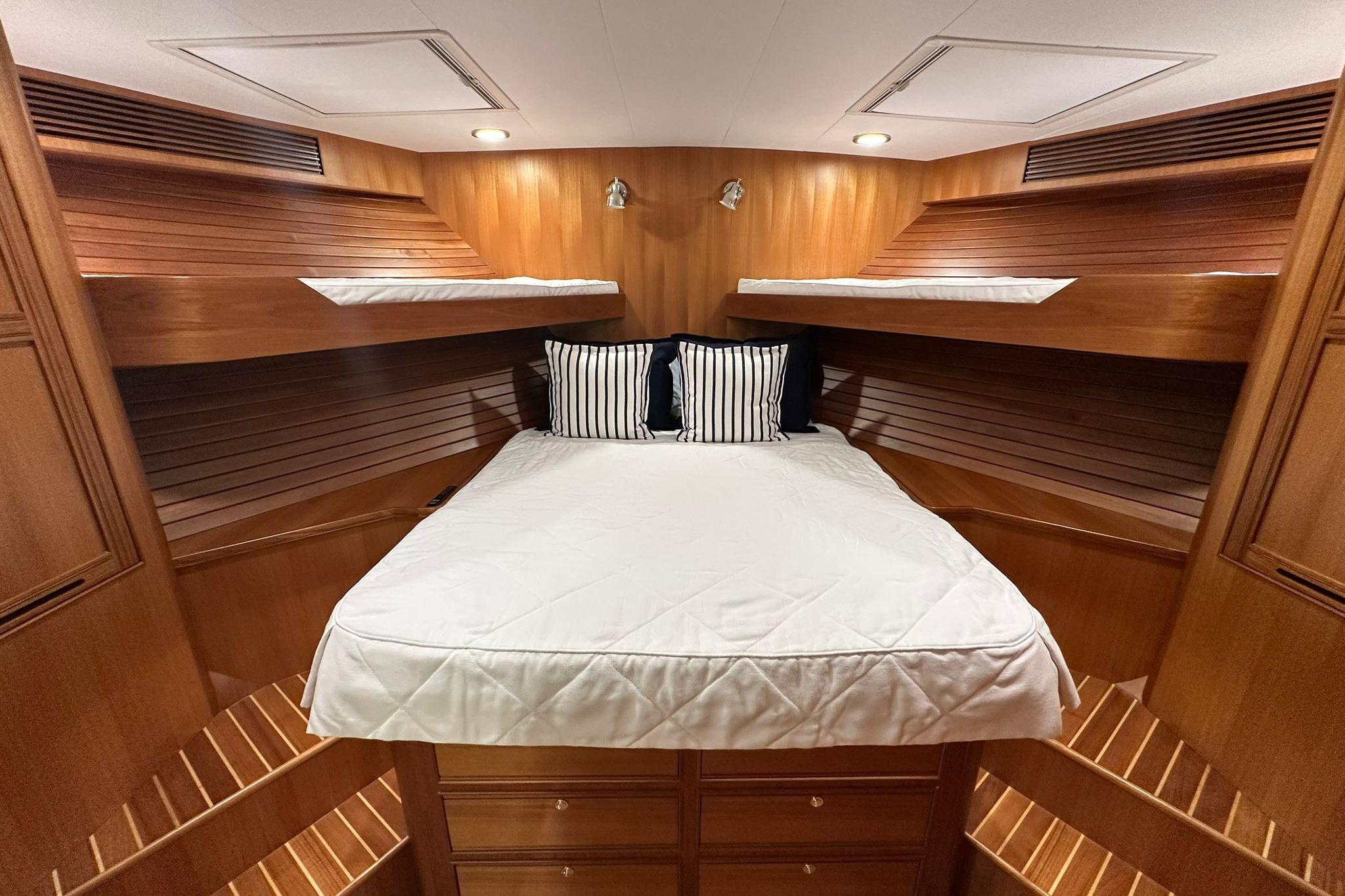 Luxurious cabin interior of 2023 Marlow Explorer 66E-CB yacht with wood finish and cozy bedding.