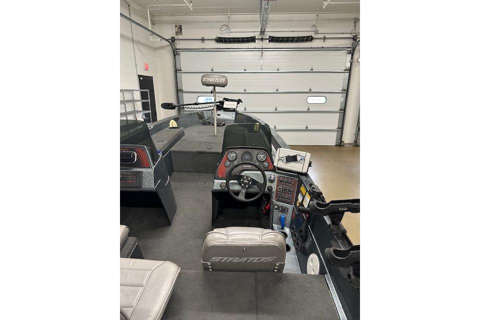 1999 Stratos 219 CF boat interior with steering wheel and control panel in a garage.