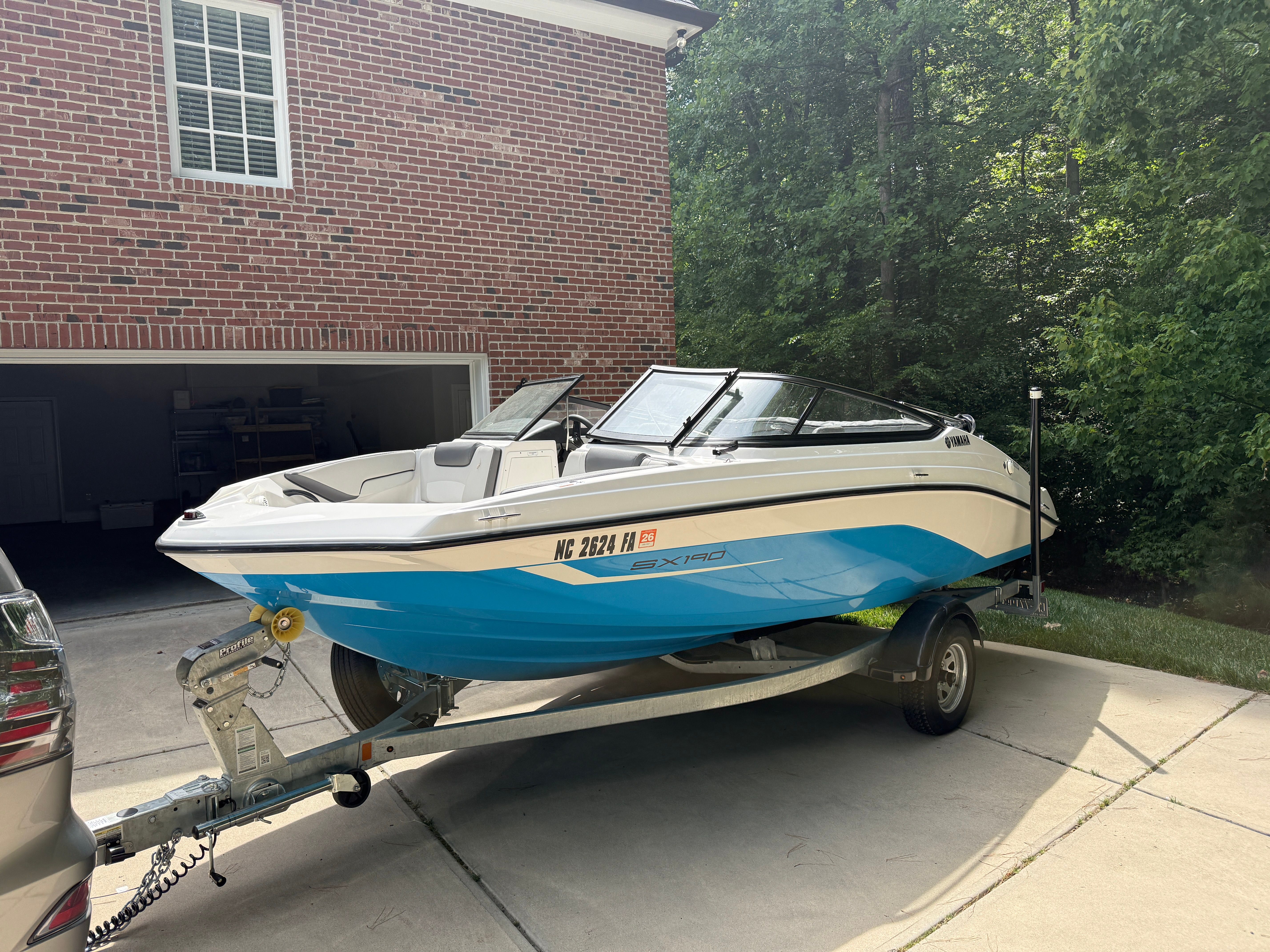 2023 Yamaha SX190 boat on trailer in front of brick building.