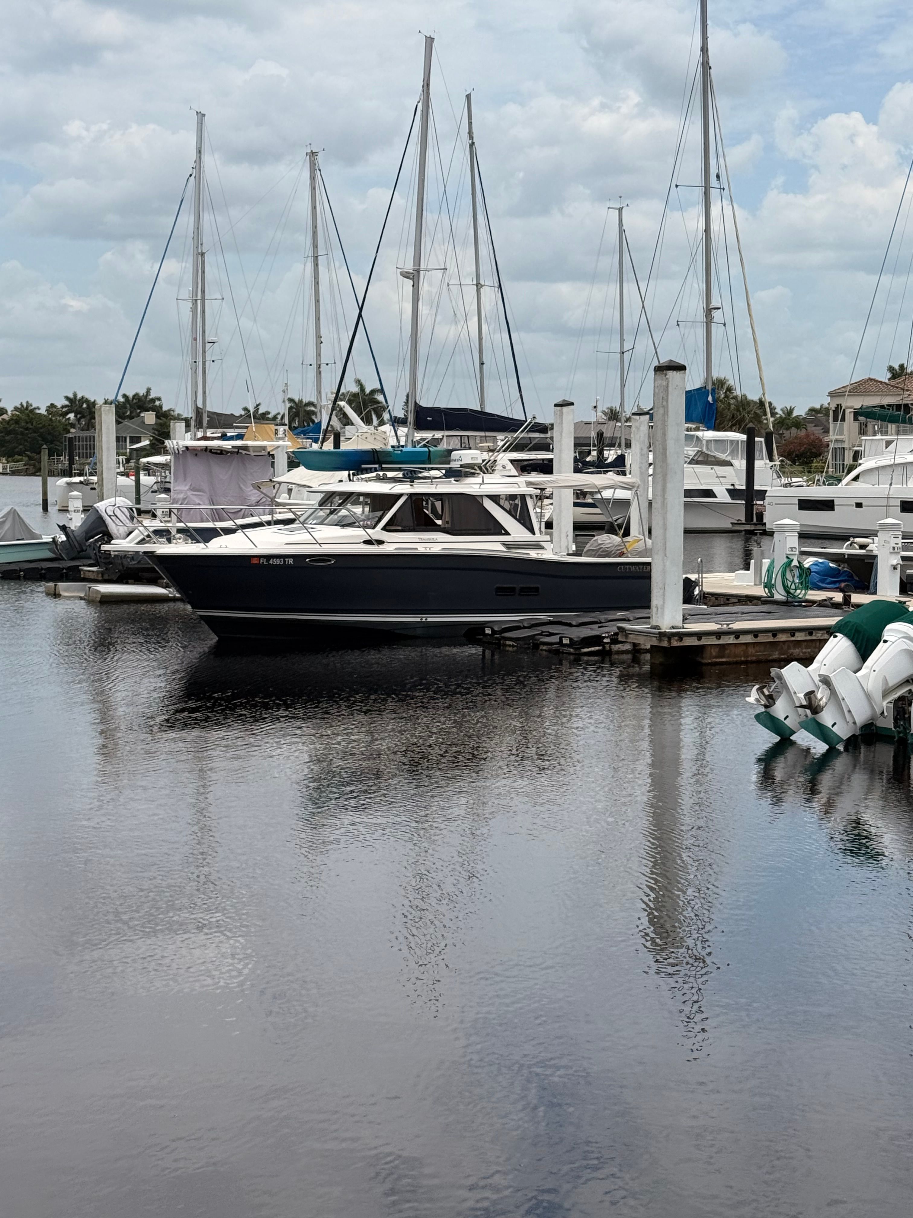 A 2023 Cutwater C-228 is docked in a calm marina, surrounded by other boats.