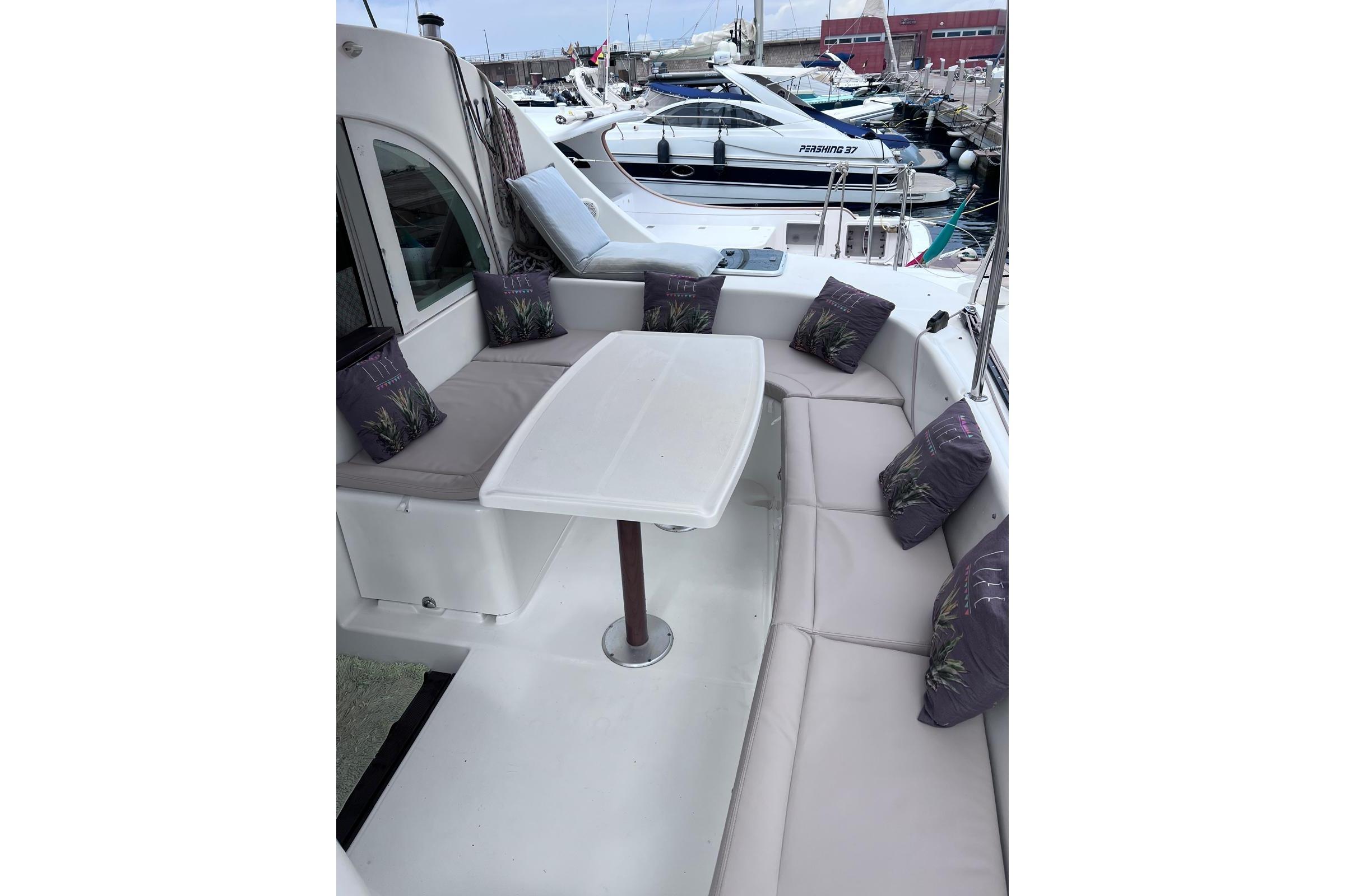 Spacious seating area on 2006 Lagoon 380 S2 yacht with cushions and table.