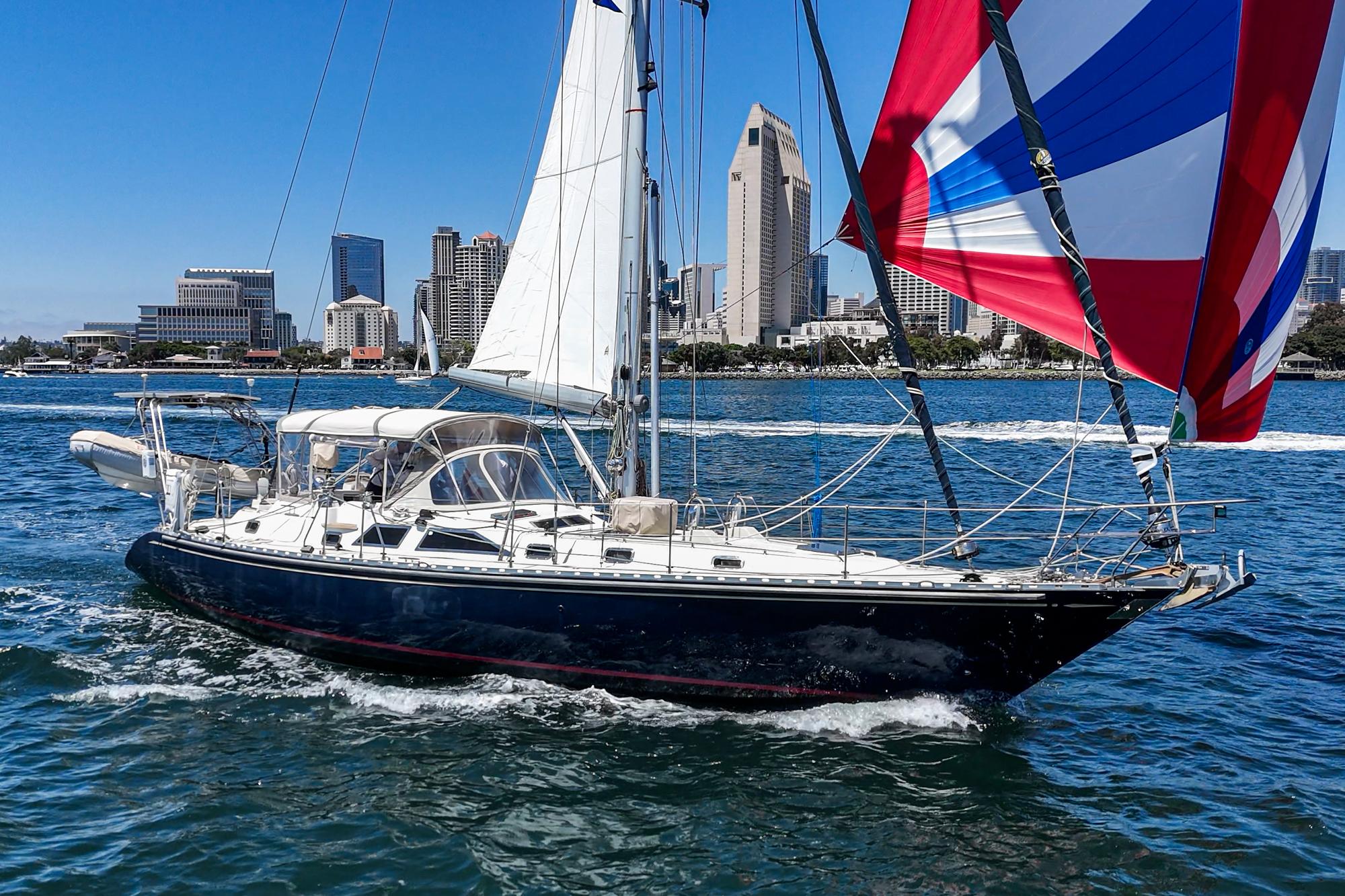 Sailing yacht Hylas 49 (2001) cruising near city skyline on a sunny day.
