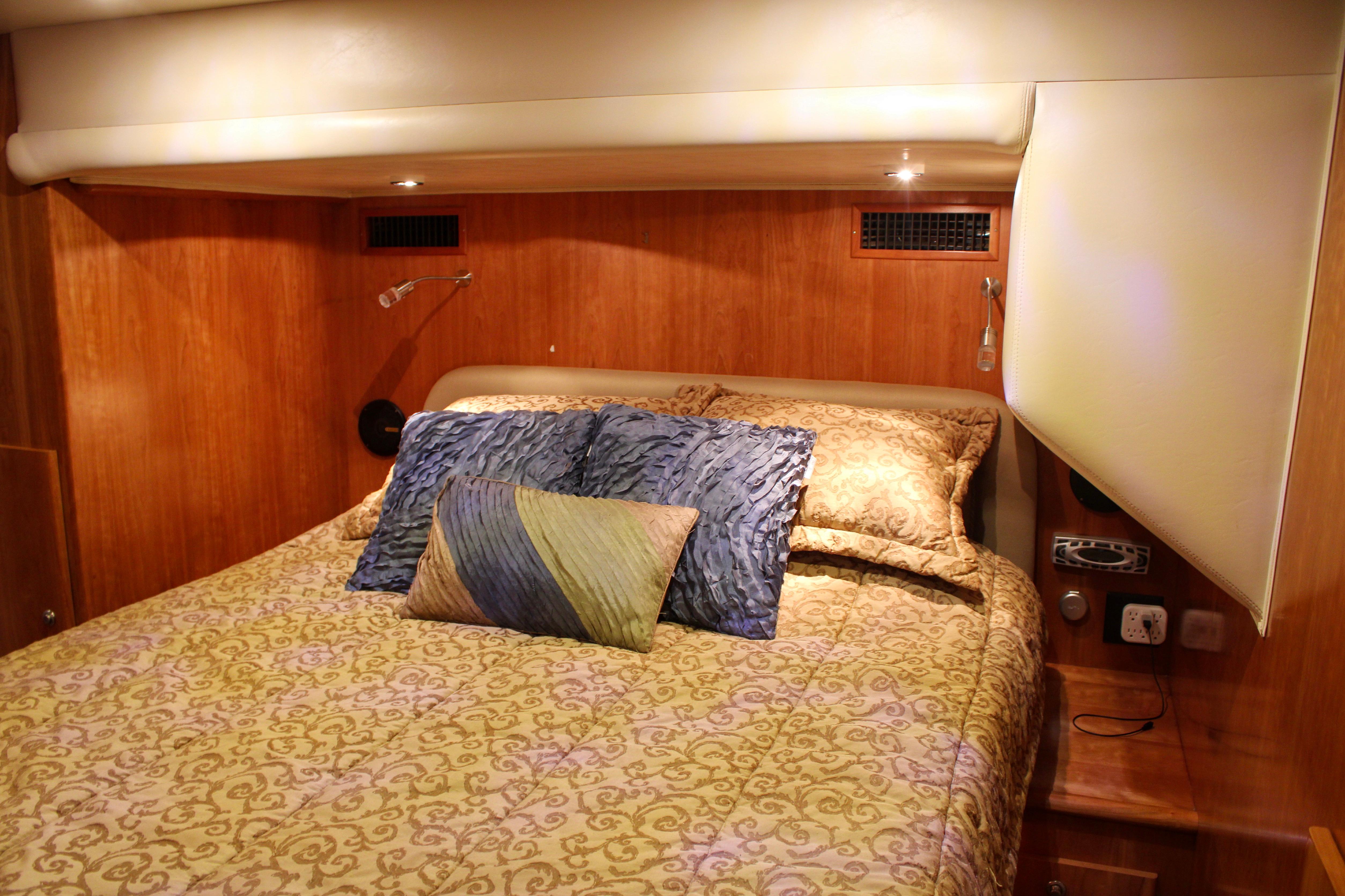 Luxurious bedroom interior of 2007 Navigator 5100 yacht with elegant bedding and wood paneling.