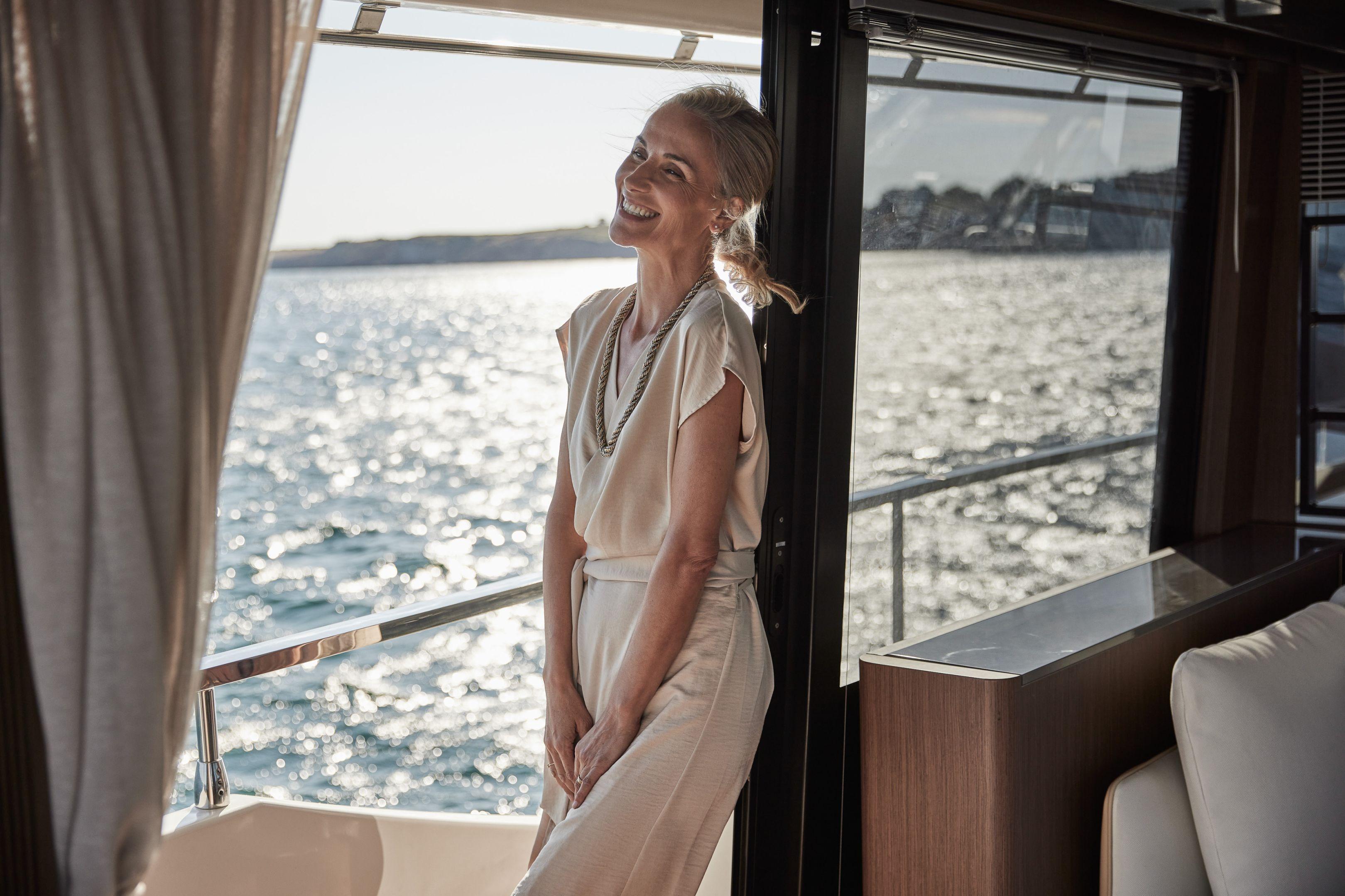 Woman enjoying the view on a 2026 Prestige X60 yacht, with ocean backdrop.