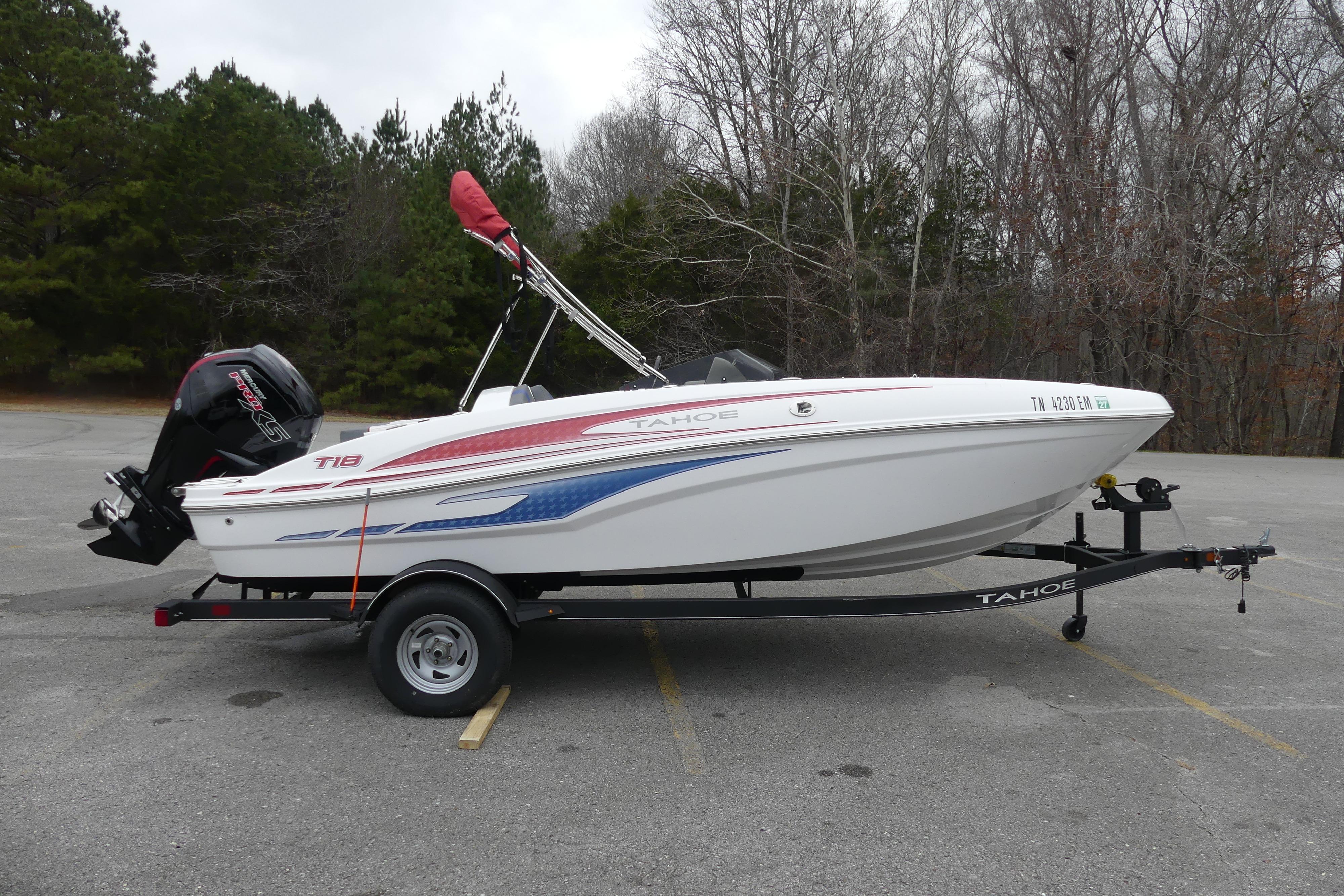 2024 Tahoe T18 boat on trailer in parking lot, surrounded by trees.