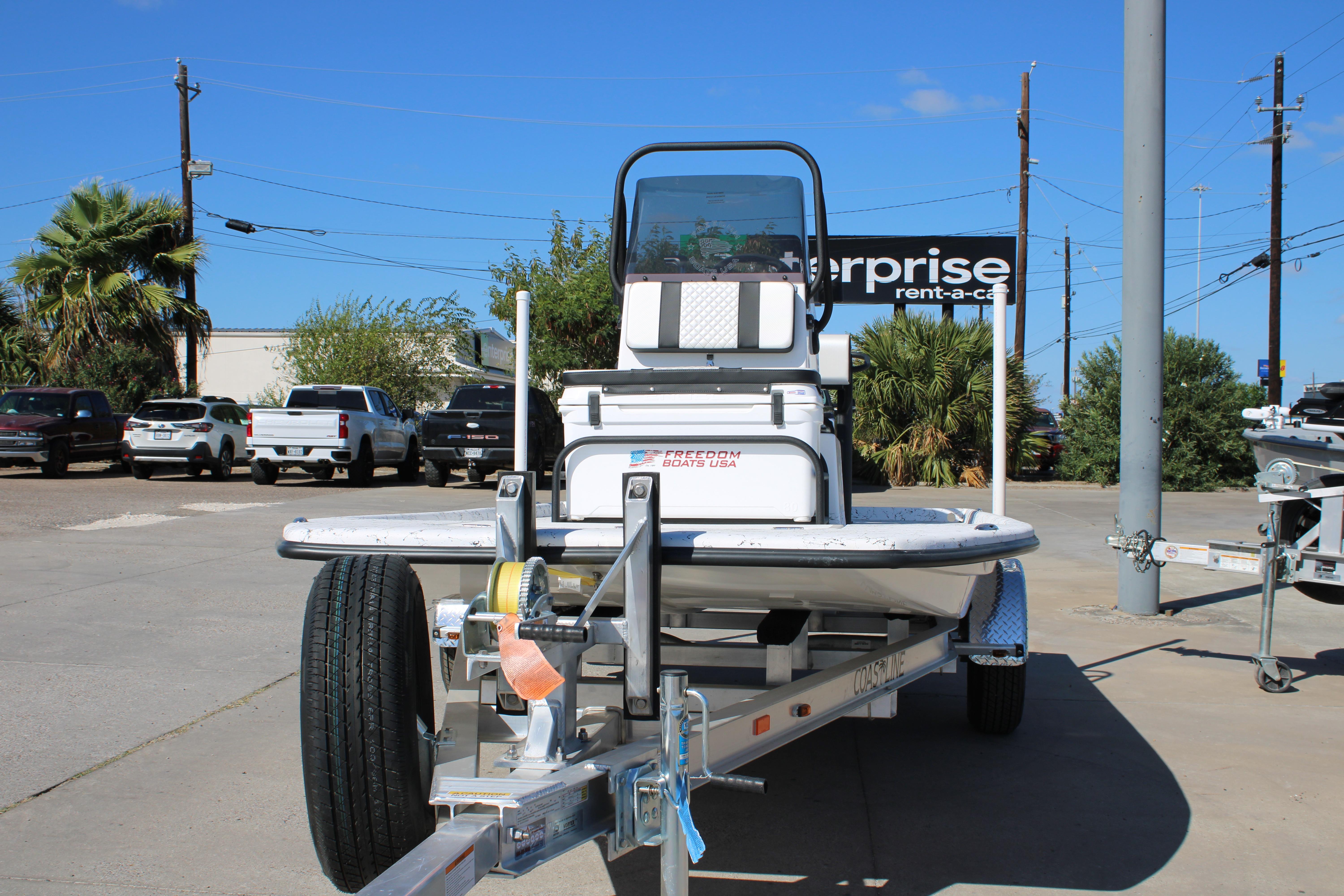 2026 Freedom Boats Chiquita on trailer in parking lot, sunny day.