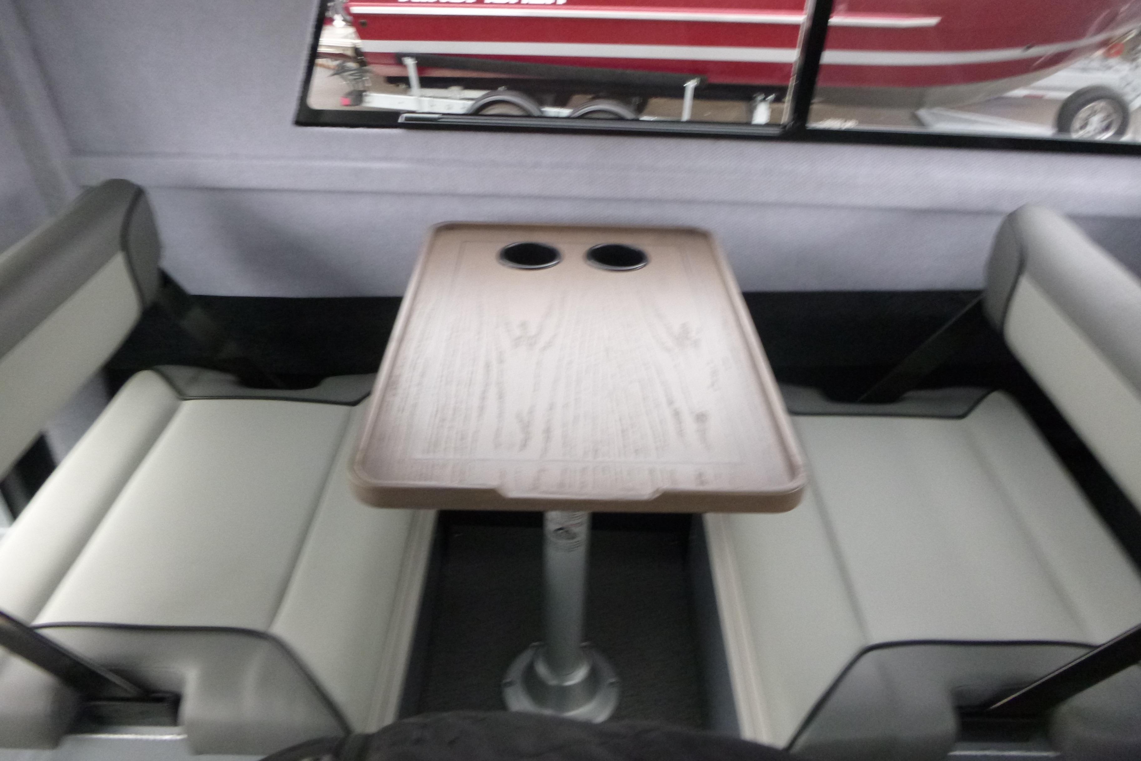 Interior seating area of 2026 KingFisher 25 XAC boat with table and cup holders.
