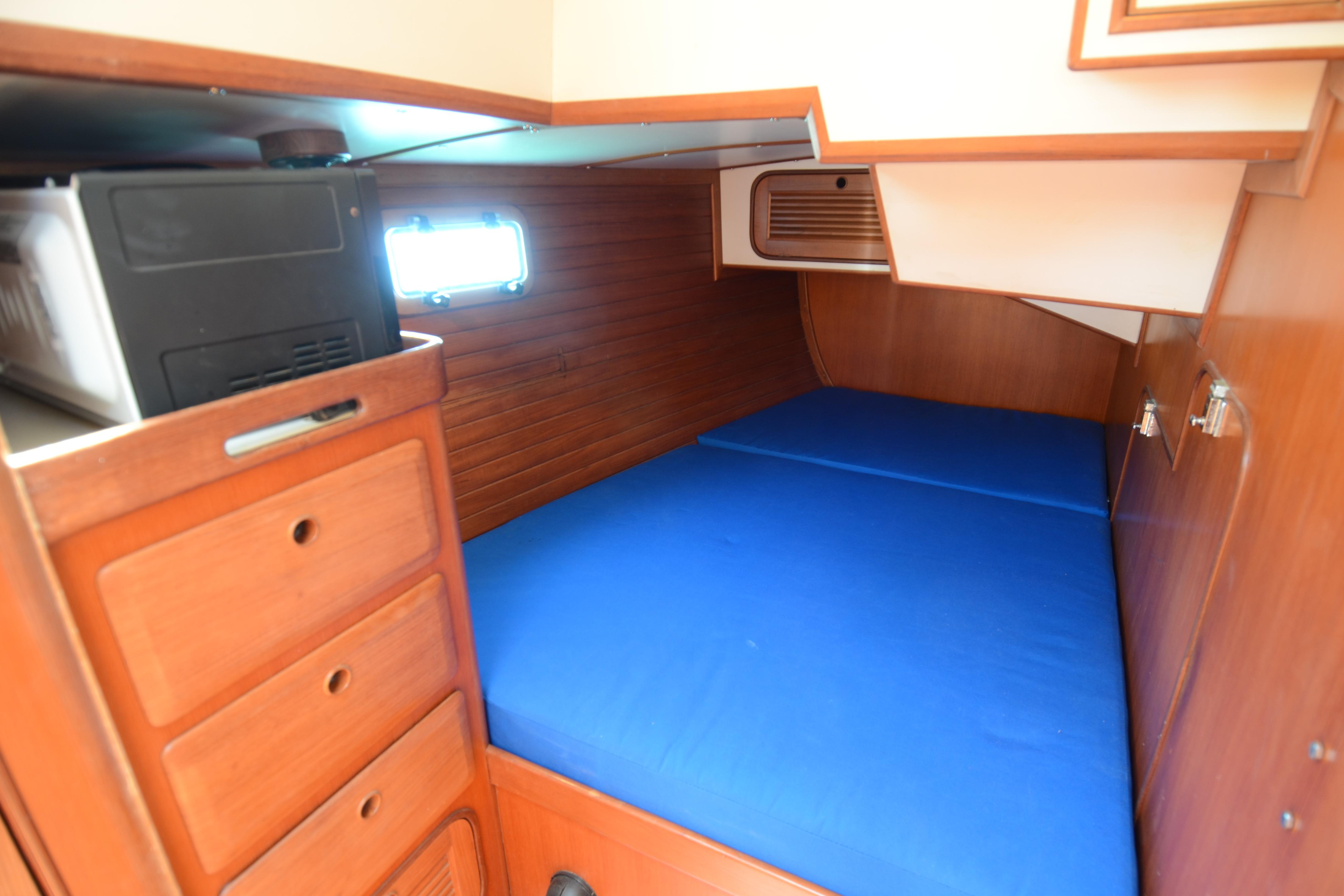 Cozy cabin interior of 1987 Norseman 400 sailboat with blue bedding and wooden storage.
