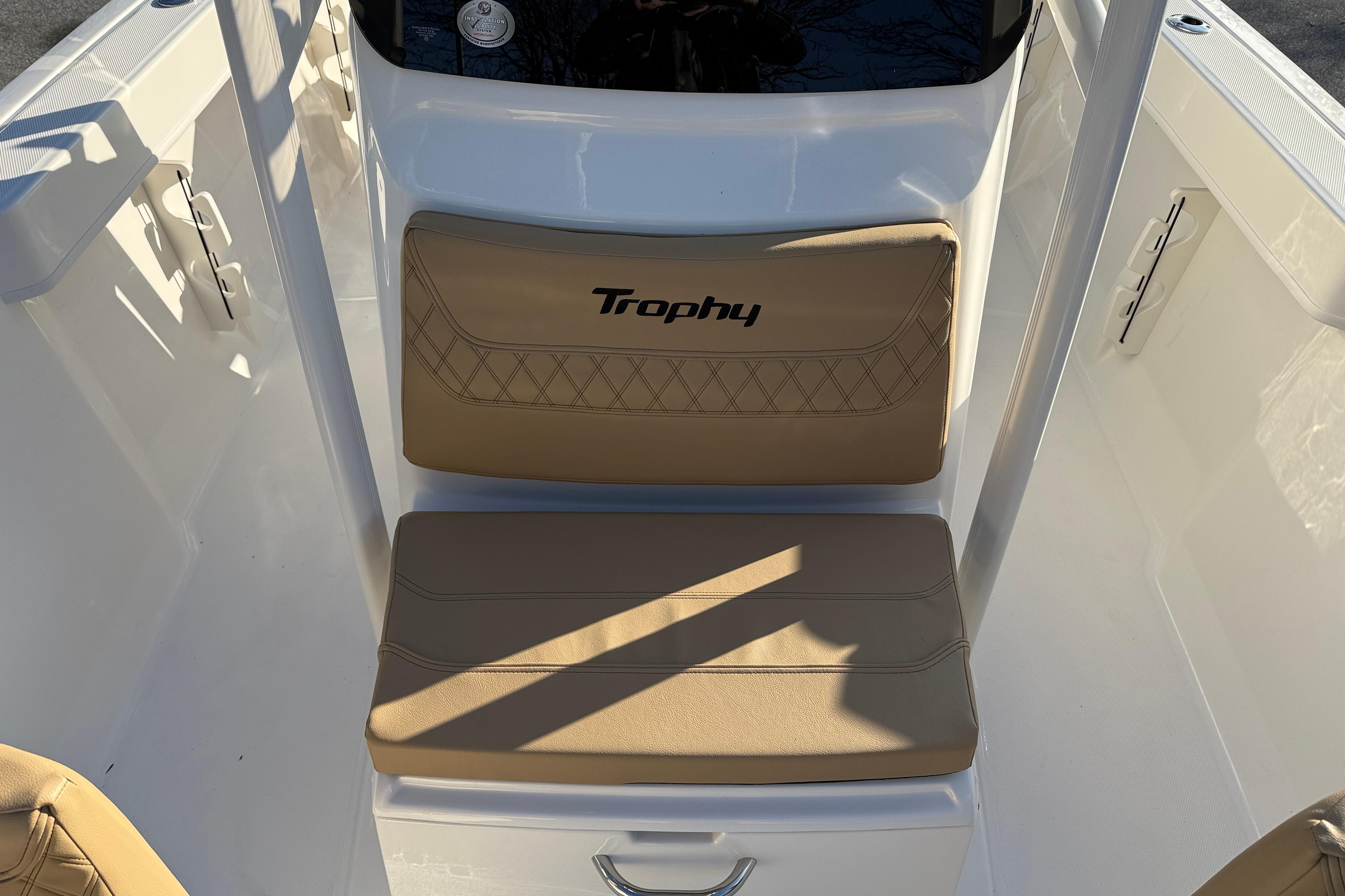 2026 Bayliner Trophy T22CC boat seating area with beige cushions and "Trophy" logo.