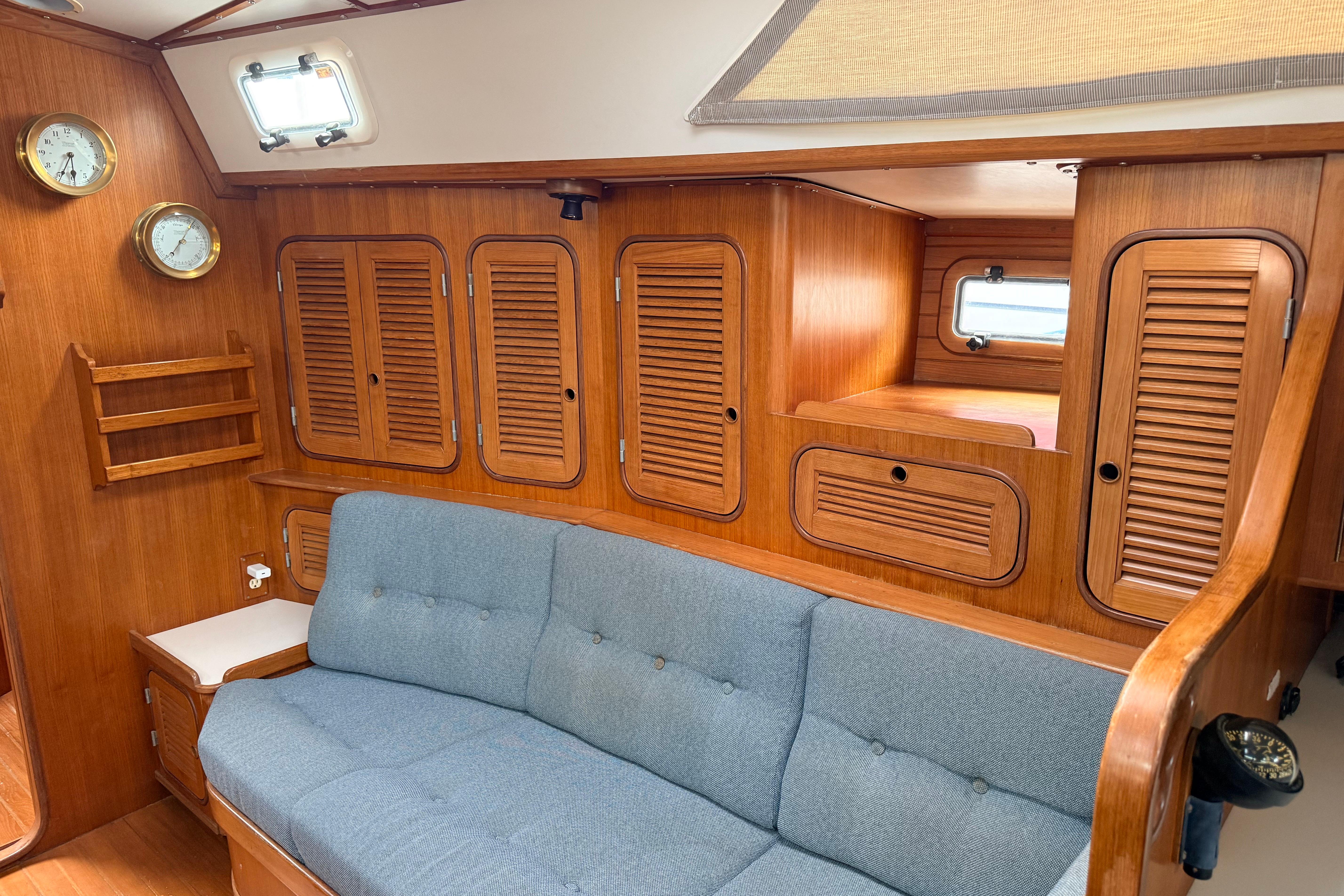Interior of 1987 Norseman 400 sailboat with wooden cabinetry and blue cushioned seating.