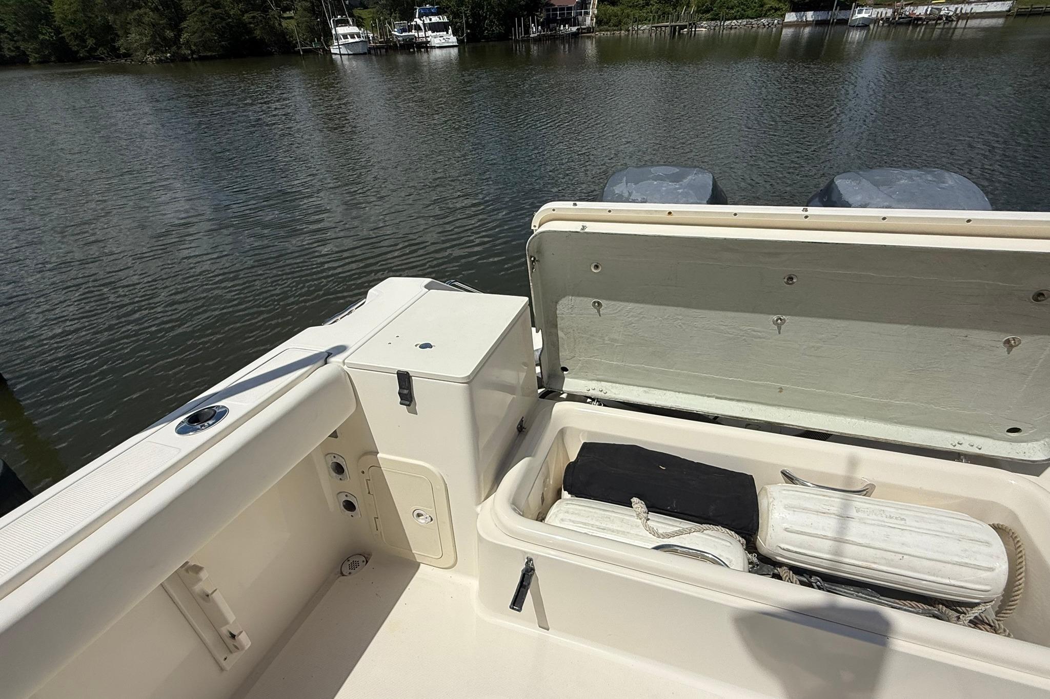 2003 Pursuit 2870 Walkaround boat with open storage compartment by a serene lake.