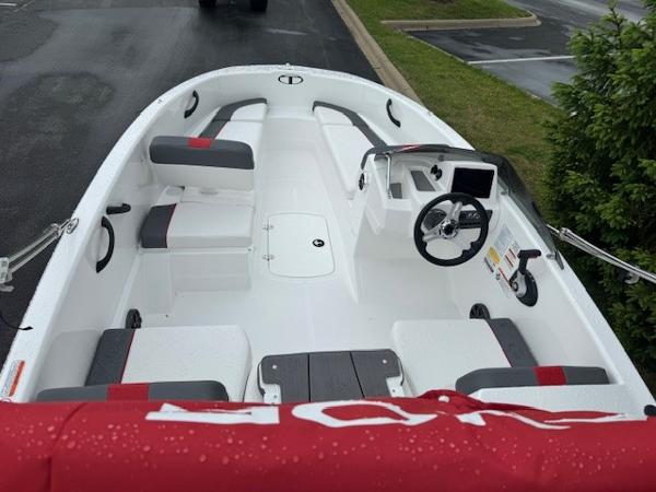 2025 Tahoe T16 boat interior with seating, steering wheel, and console, parked on wet pavement.