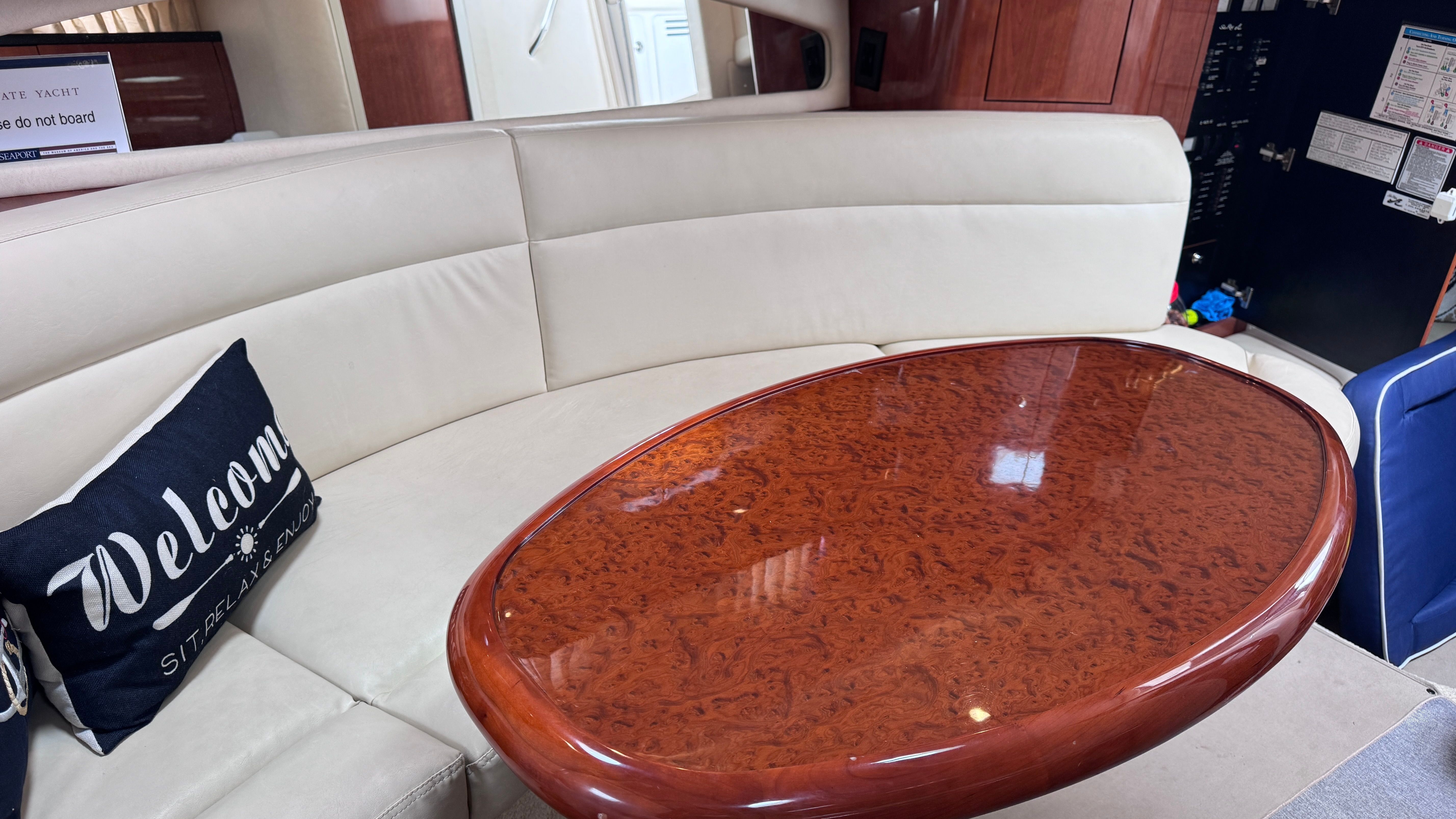 Interior of a 2003 Sea Ray 360 Sundancer with an elegant wooden table and beige sofa.