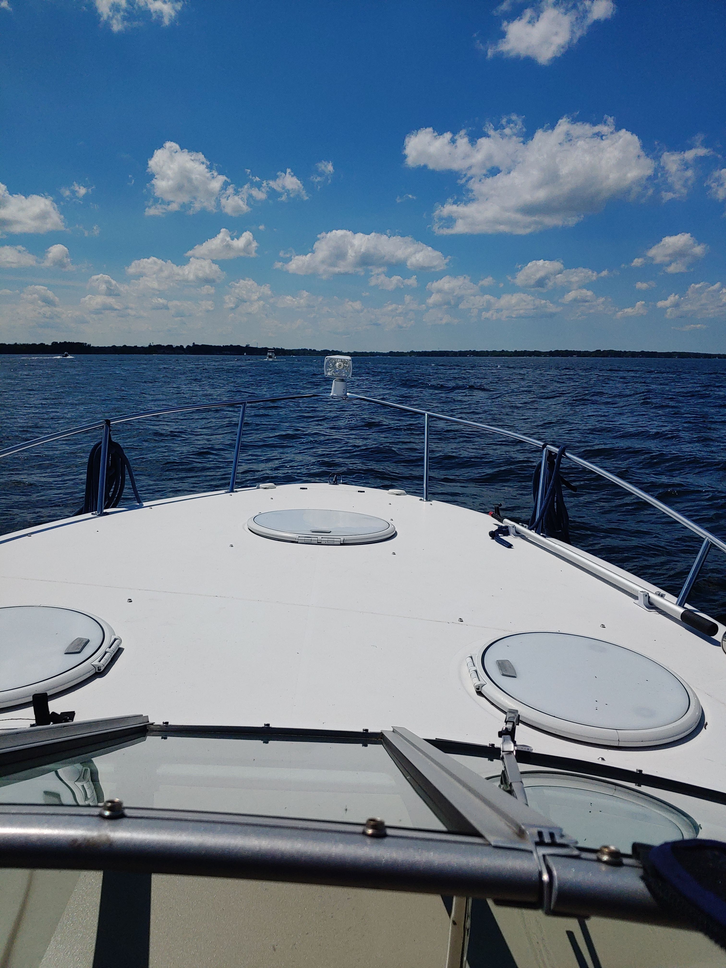 Boat on calm water under a blue sky with white clouds.