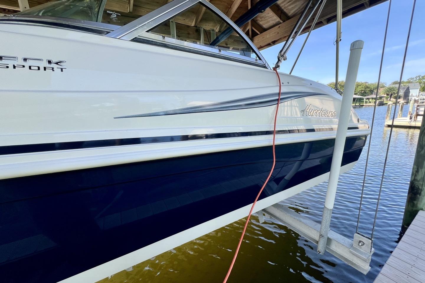 2013 Hurricane SunDeck 187 OB boat docked, featuring sleek design and blue accents.
