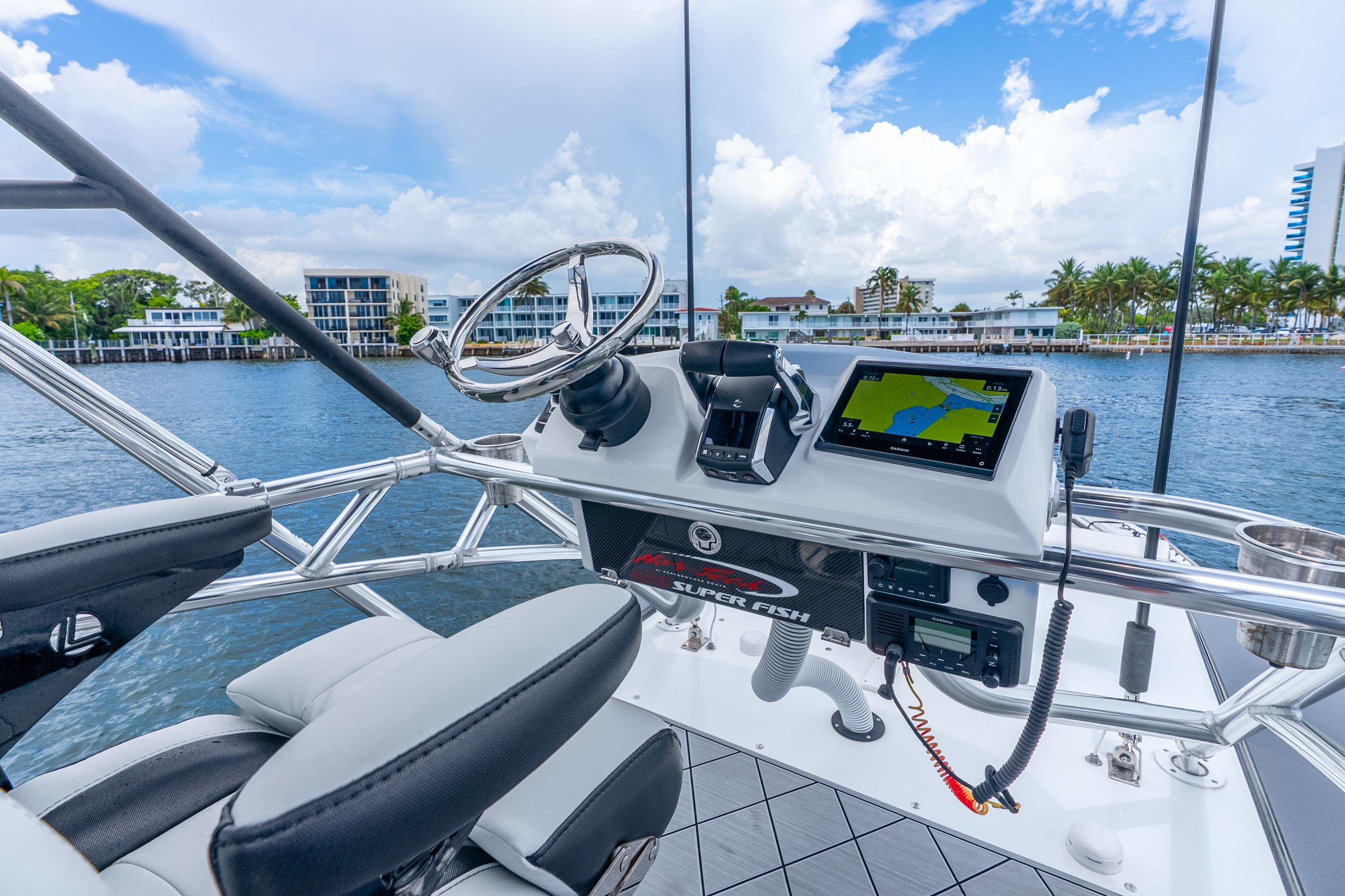 2024 Nor-Tech 452 Super Fish boat helm with navigation system, steering wheel, and waterfront view.