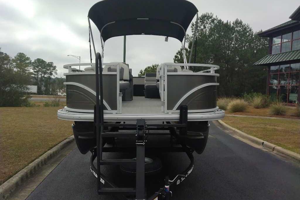2026 Sun Tracker Fishin' Barge 22 DLX pontoon boat on trailer, parked outdoors.