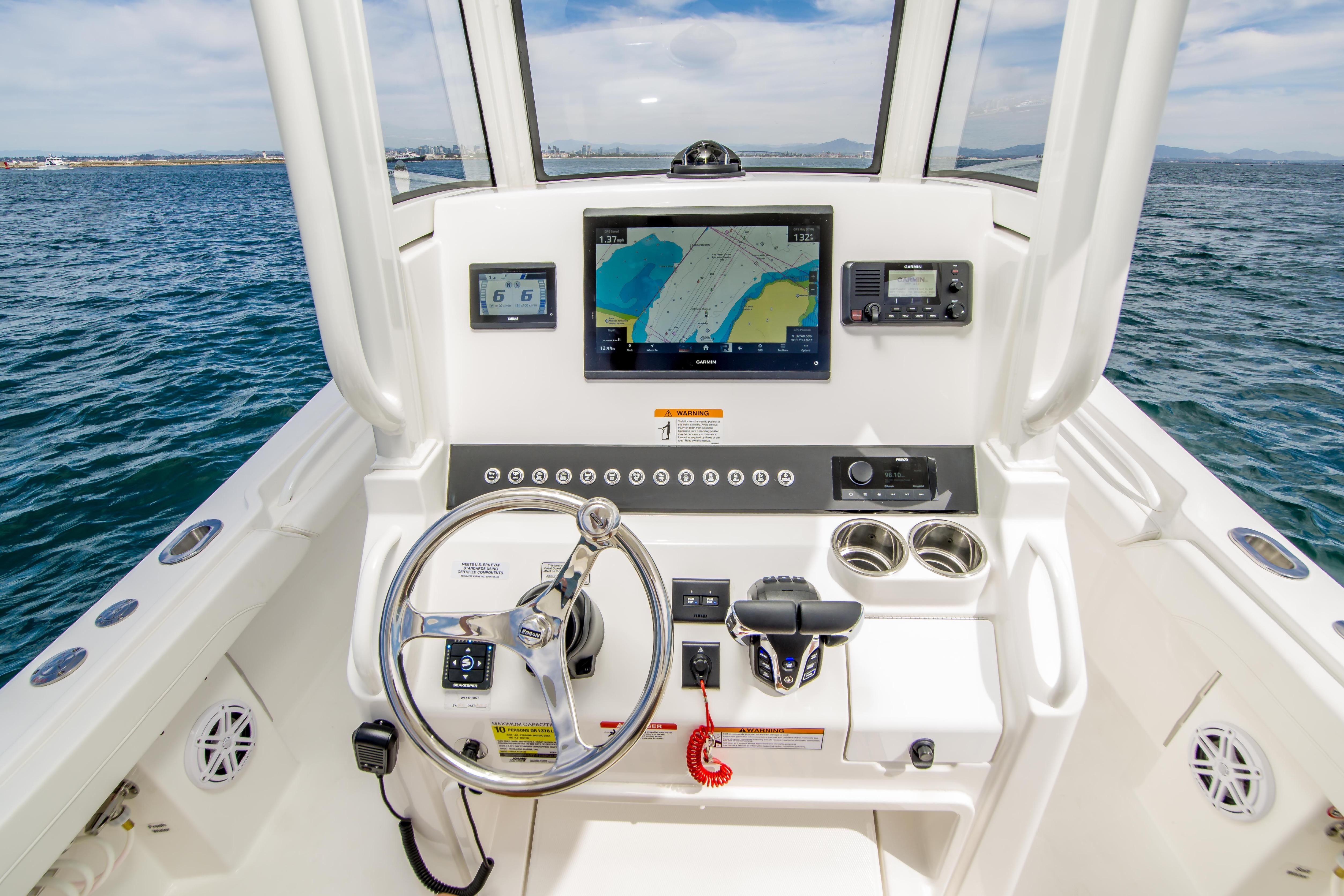 2026 Regulator 23 boat helm with navigation screens and steering wheel on open water.