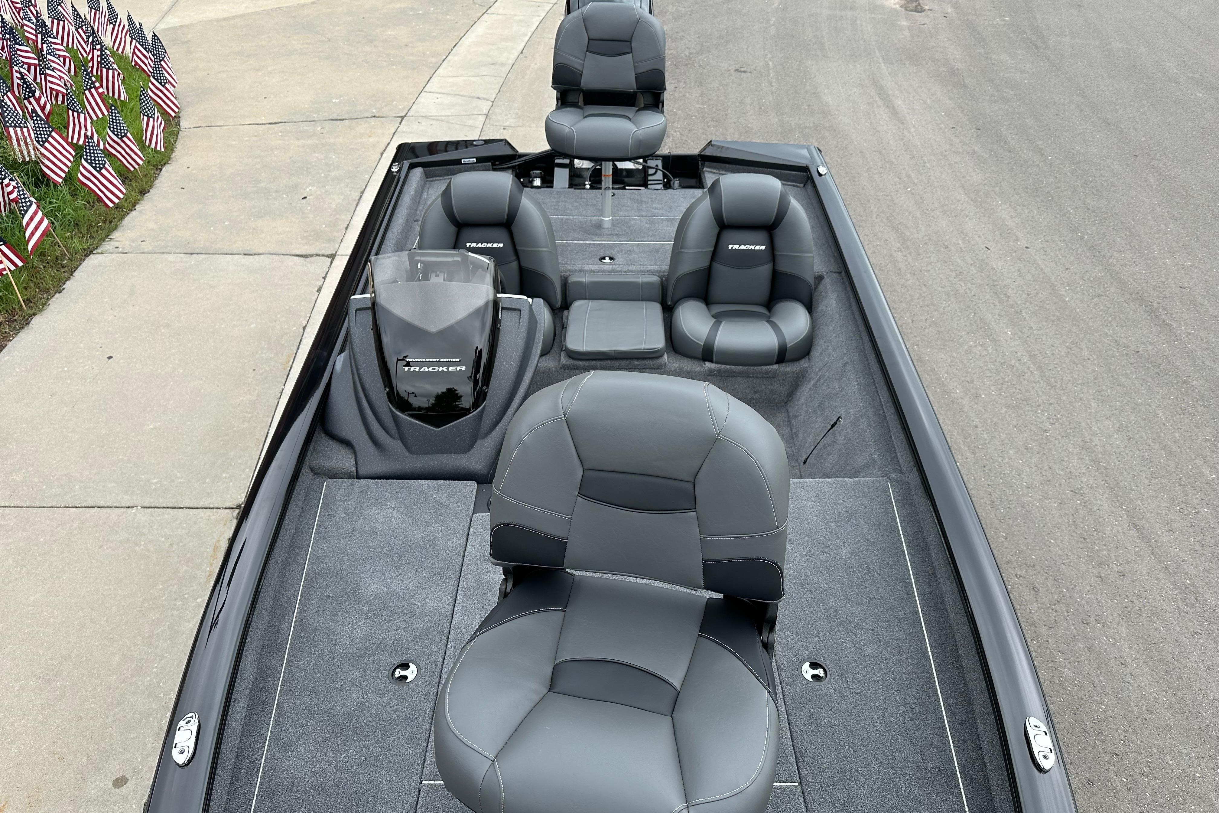 2026 Tracker Pro Team 190 boat interior with gray seating, parked near American flags.