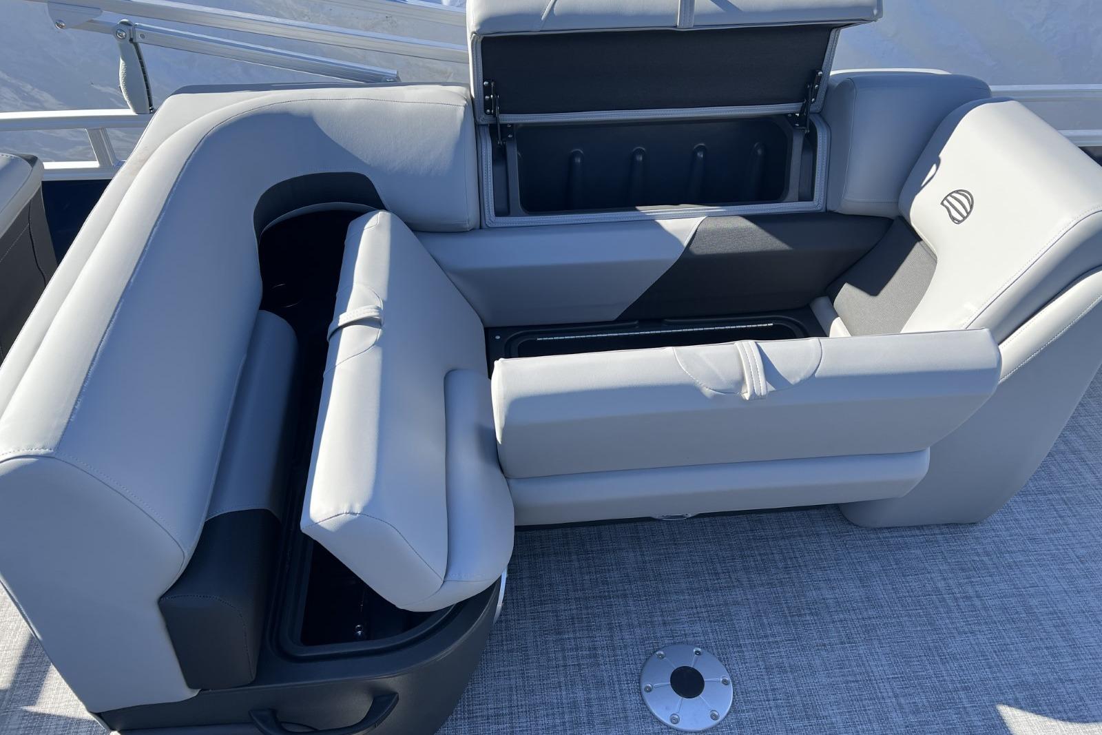 2026 Sun Tracker SportFish 22 DLX boat with open storage compartments and cushioned seating.