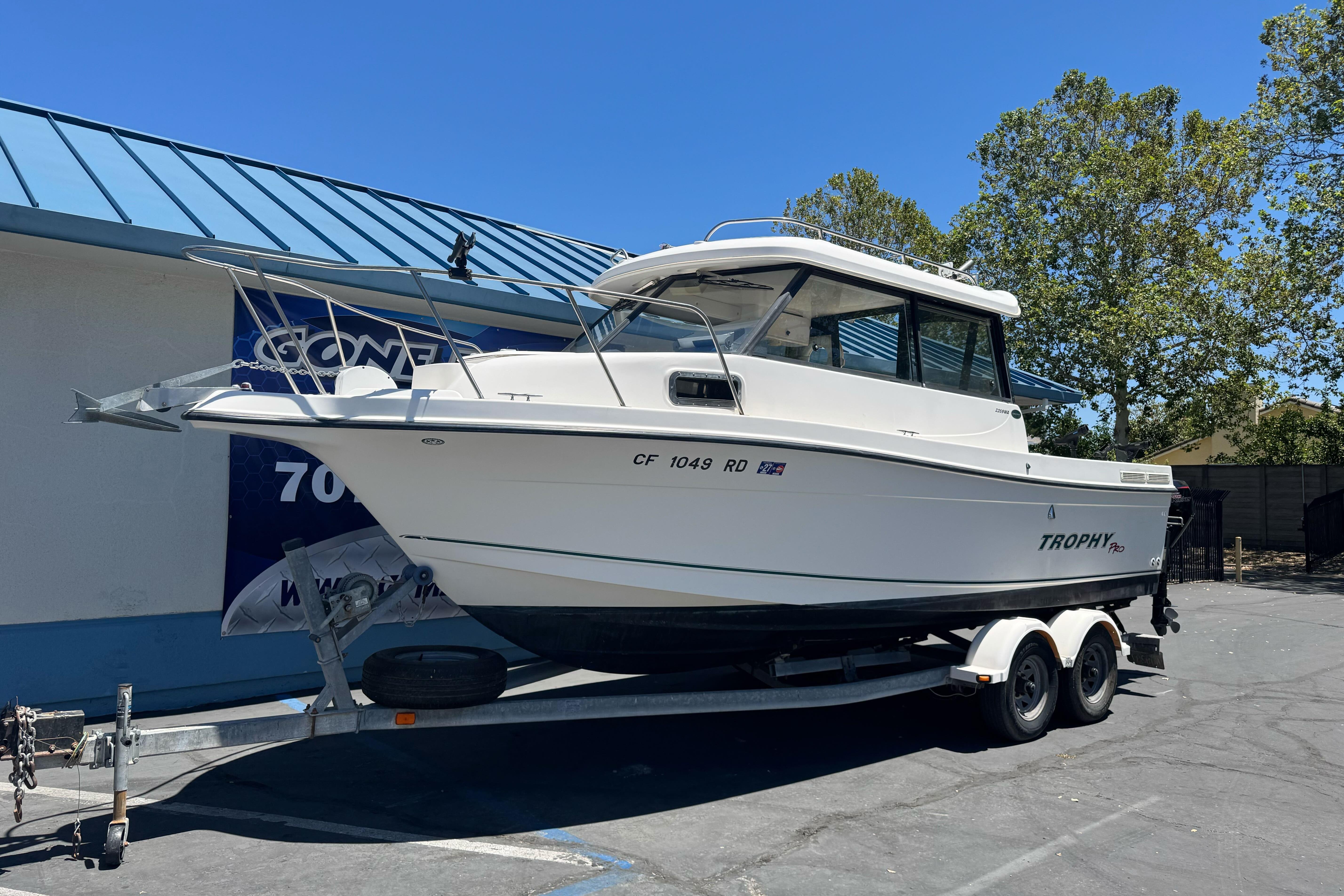 2004 Trophy 2359 WA boat on trailer, parked outdoors under clear blue sky.