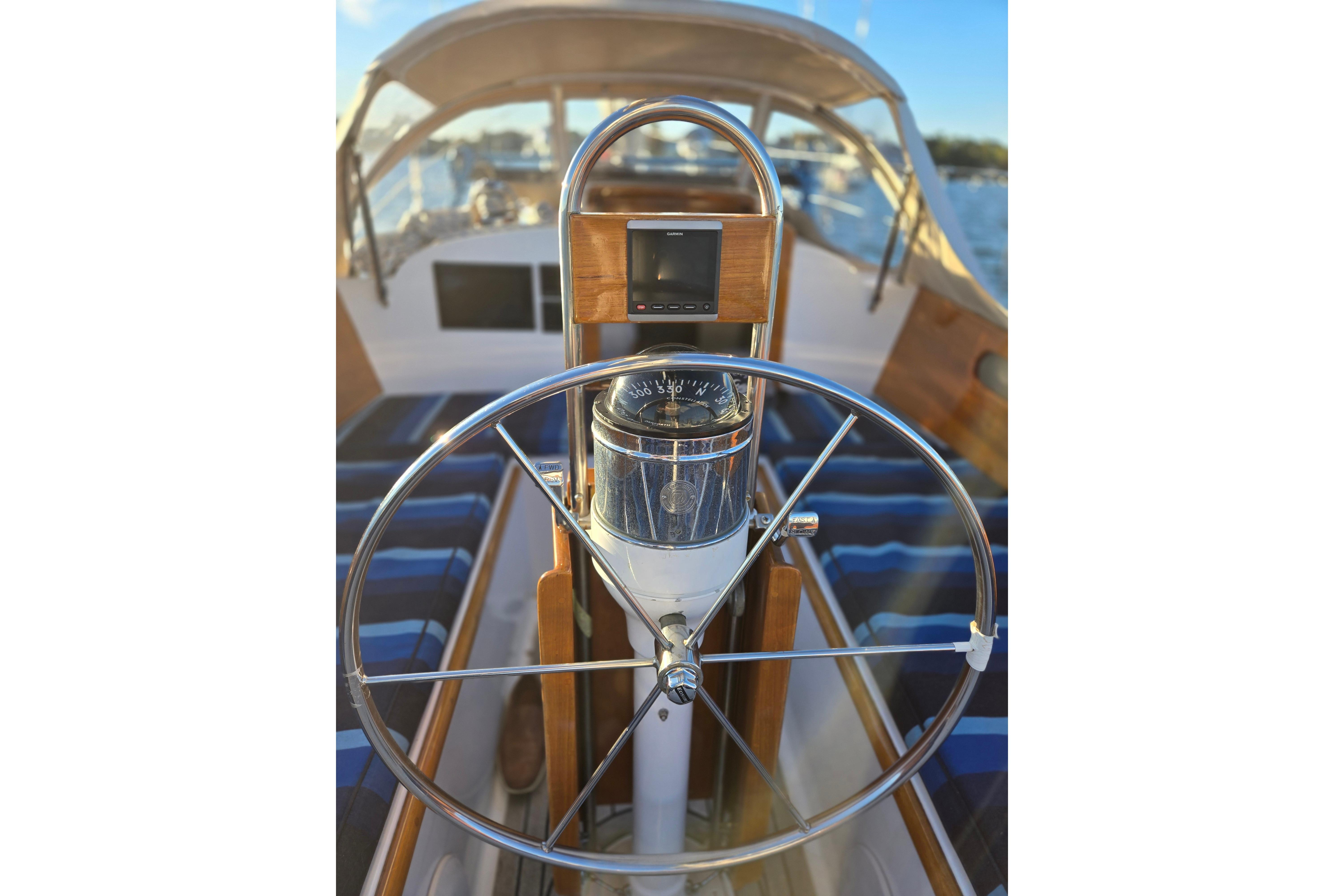 Steering wheel of a 1970 Hinckley Bermuda 40 sailboat with compass and navigation equipment.