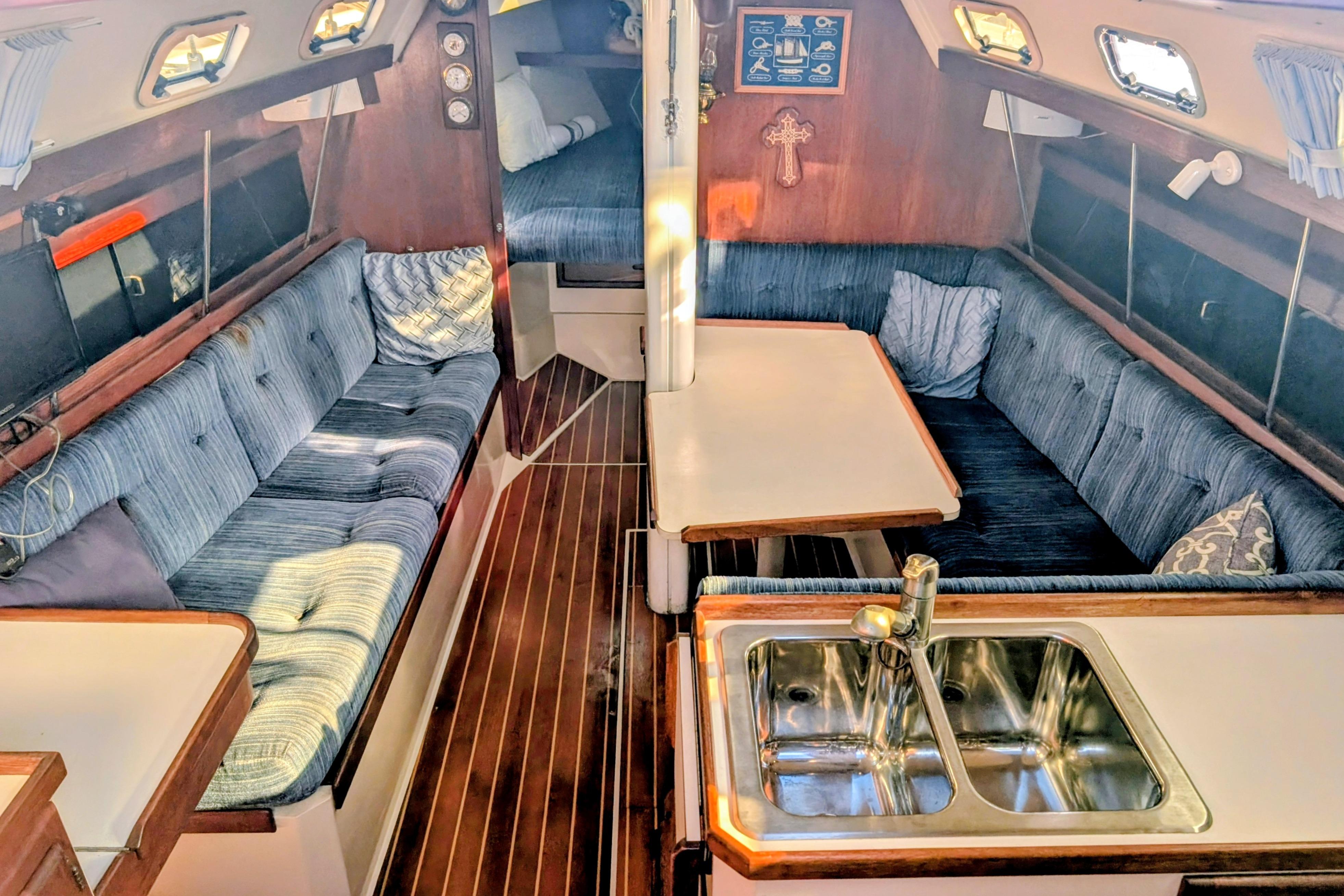 Interior of a 1989 Catalina 34 sailboat with cozy seating and a compact kitchen area.