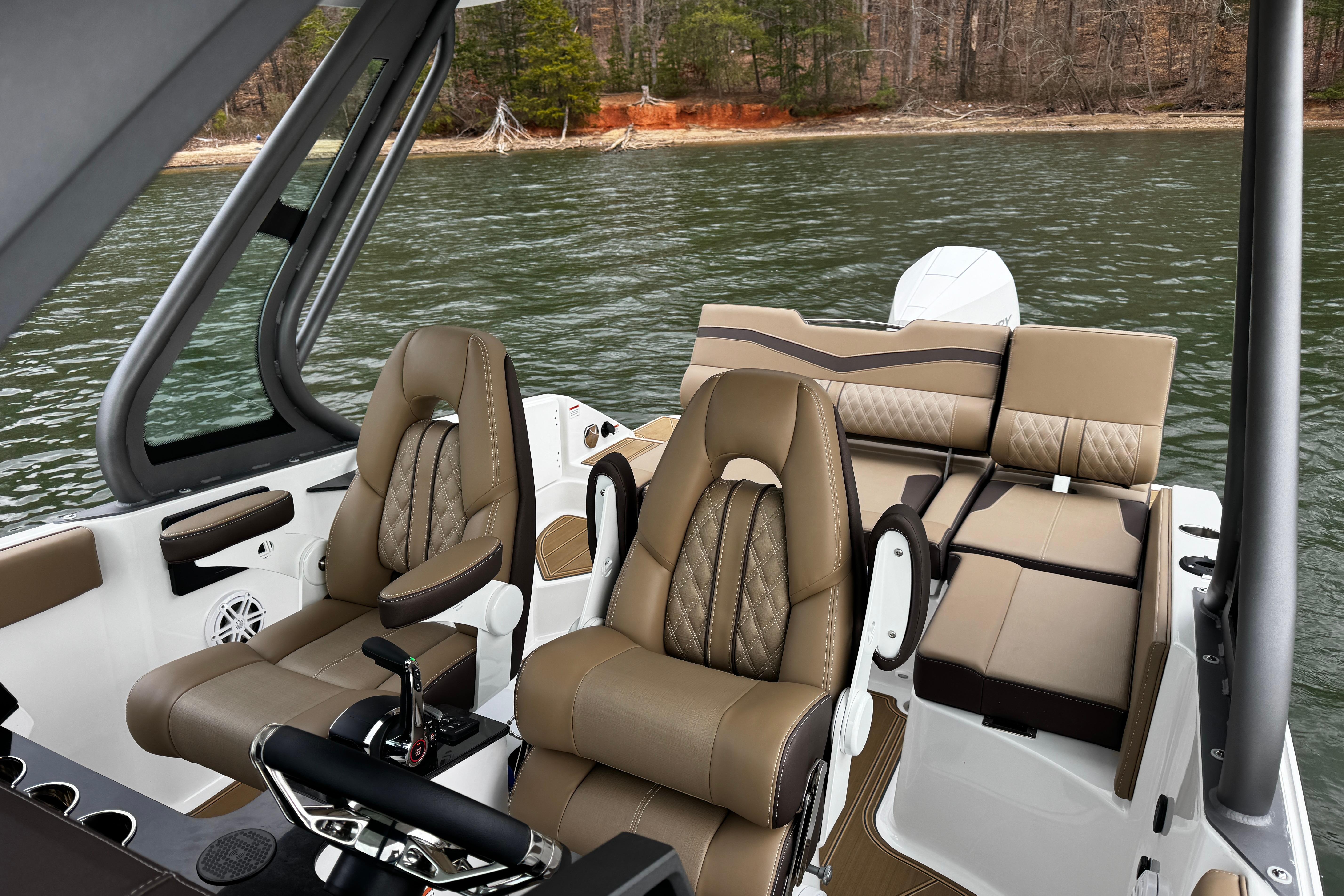 2026 Monterey Elite 25 OB boat interior with luxurious seating on a serene lake.