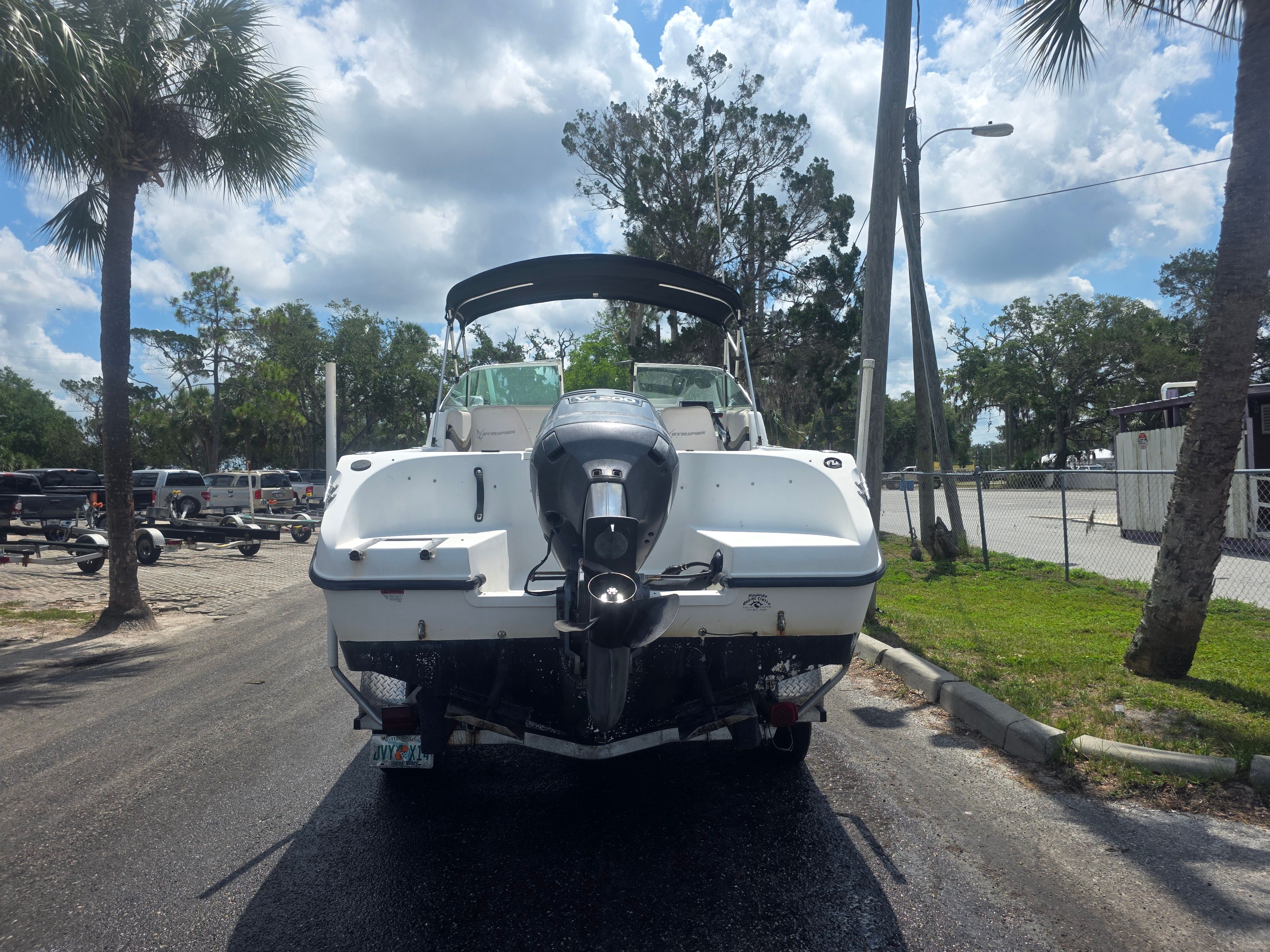 A 2002 Seaswirl Striper 2101 DC on a trailer, surrounded by trees and a cloudy sky.