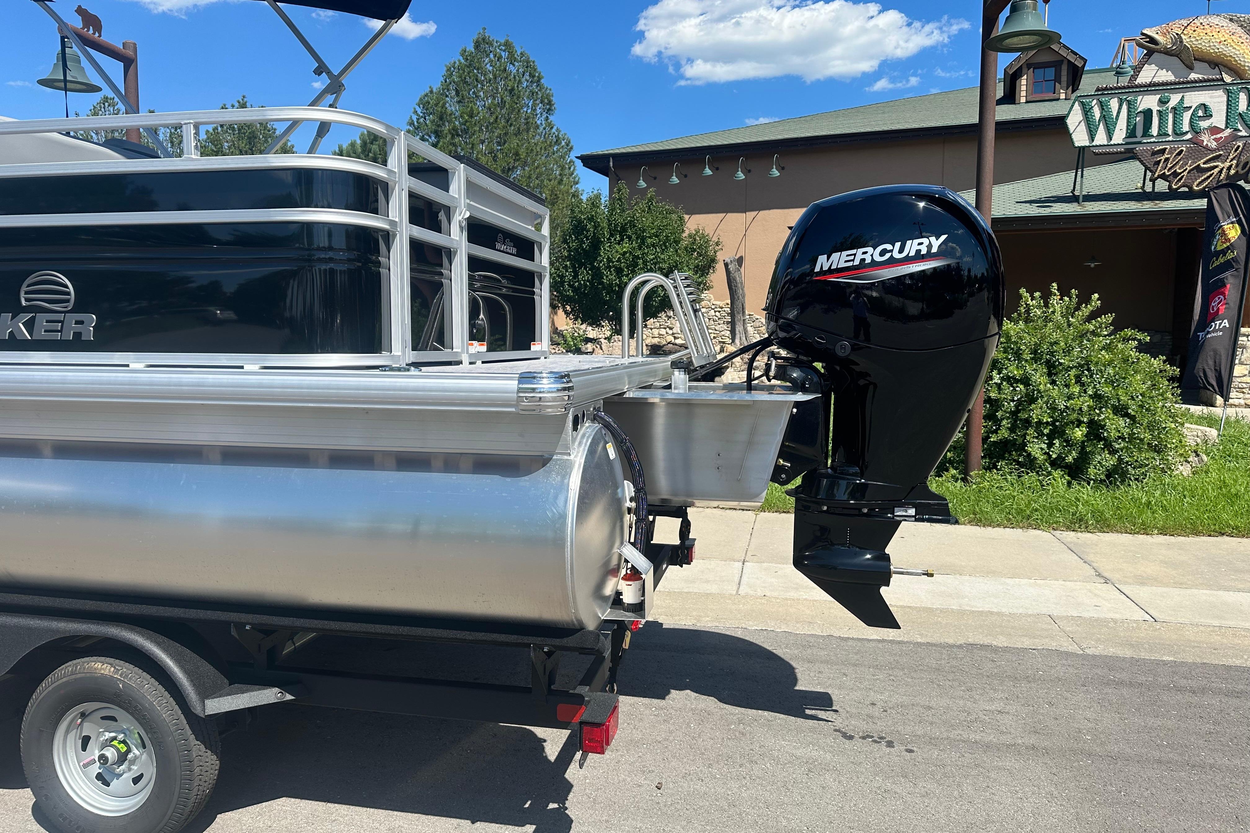 2026 Sun Tracker SportFish 22 DLX pontoon boat with Mercury outboard motor on trailer.