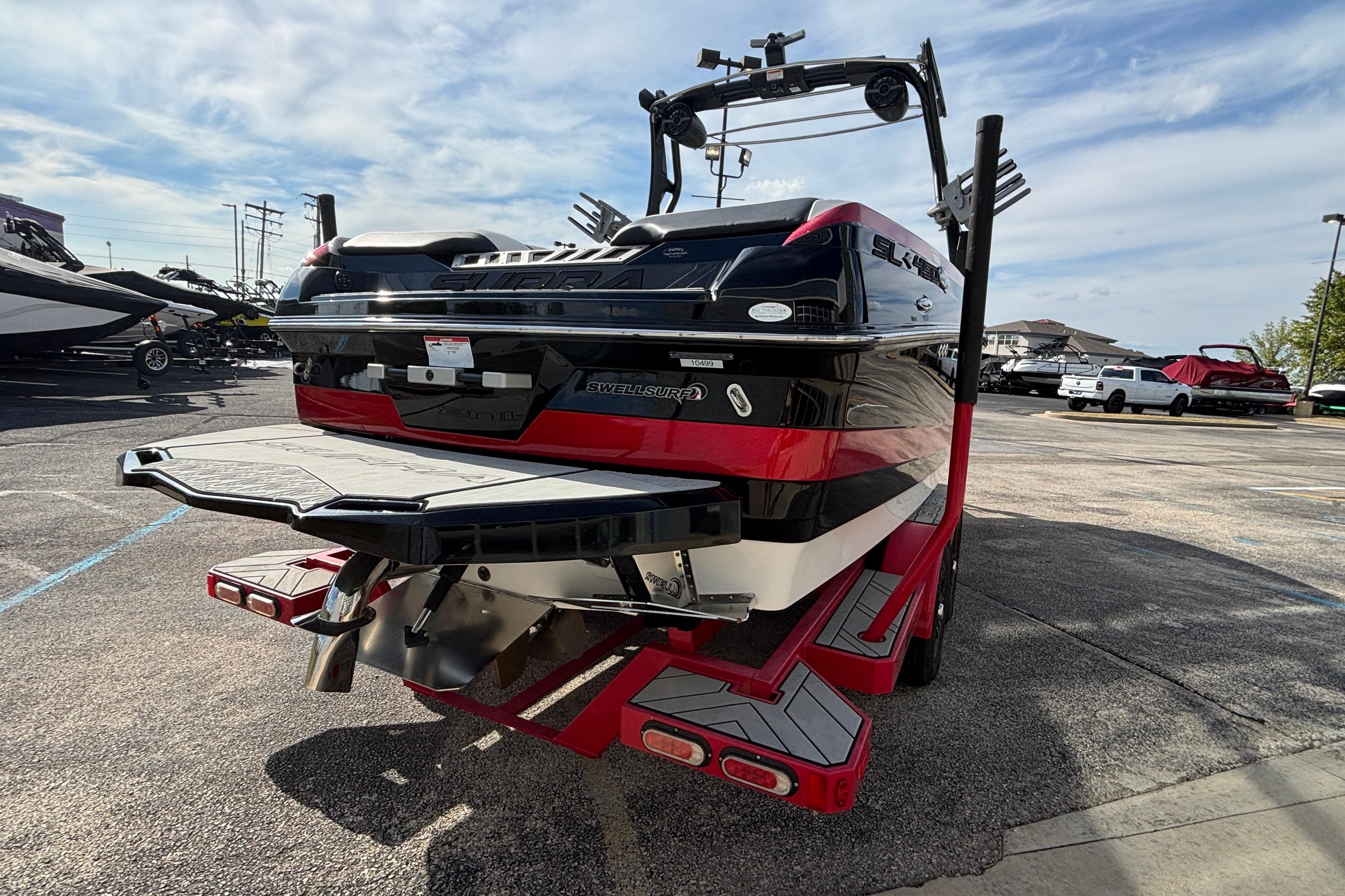 2019 Supra SL 450 boat with red and black design, parked on a trailer.