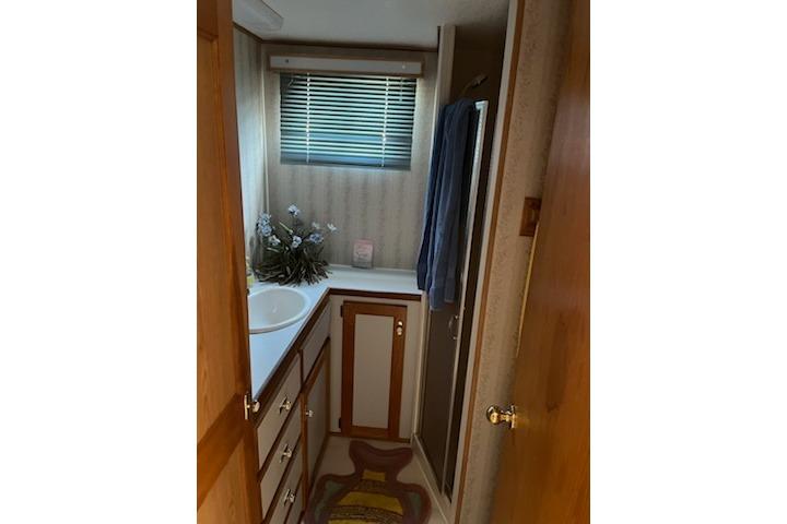 Compact bathroom in 1994 PlayCraft 5215 RV with sink, cabinets, and window blinds.