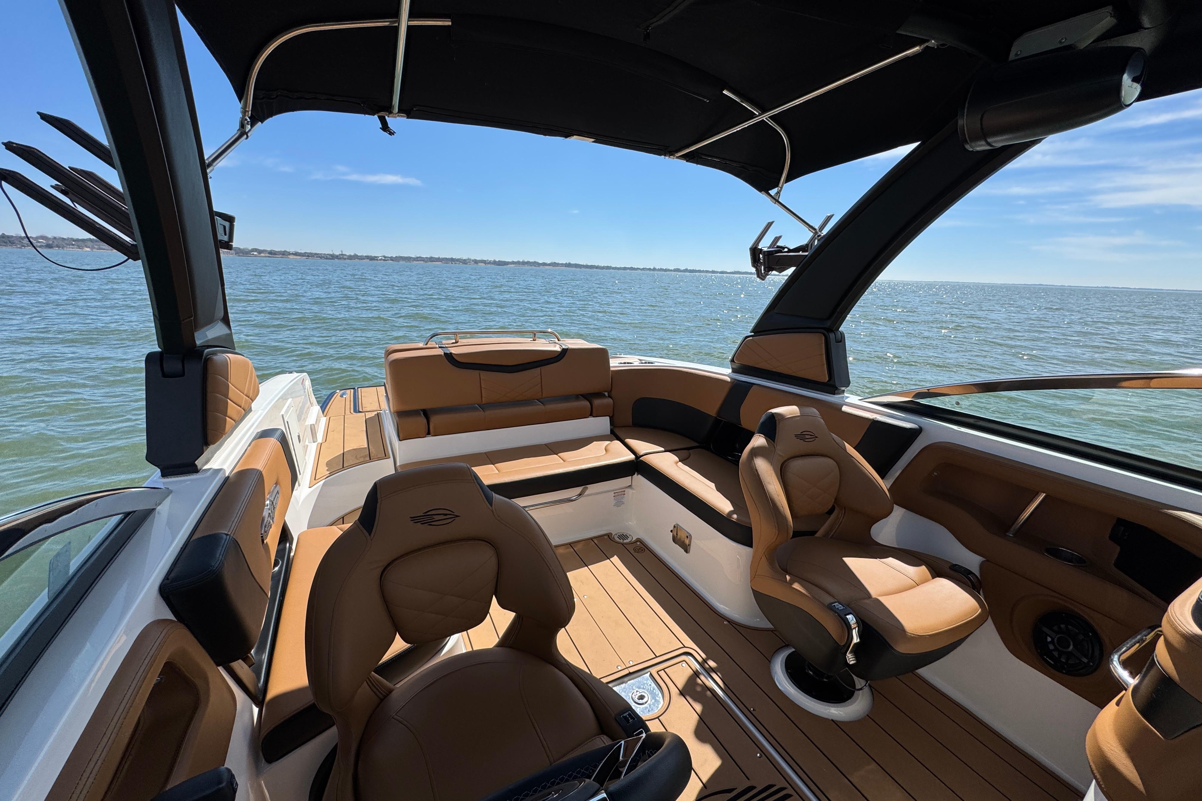 Luxurious interior of 2023 Chaparral 26 Surf boat with tan seating on open water.