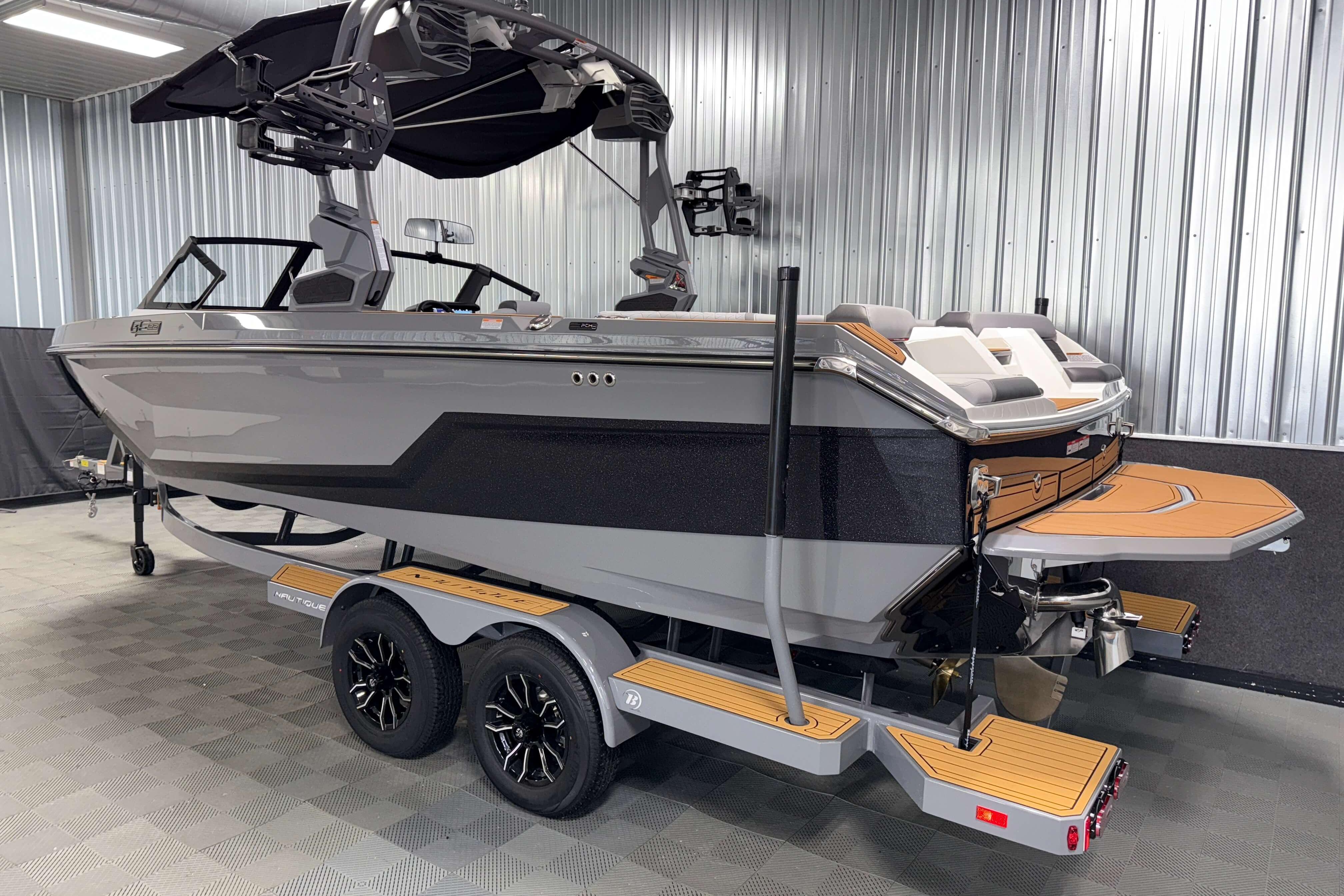2026 Nautique Super Air Nautique GS22 boat in showroom, sleek design, dual-axle trailer.