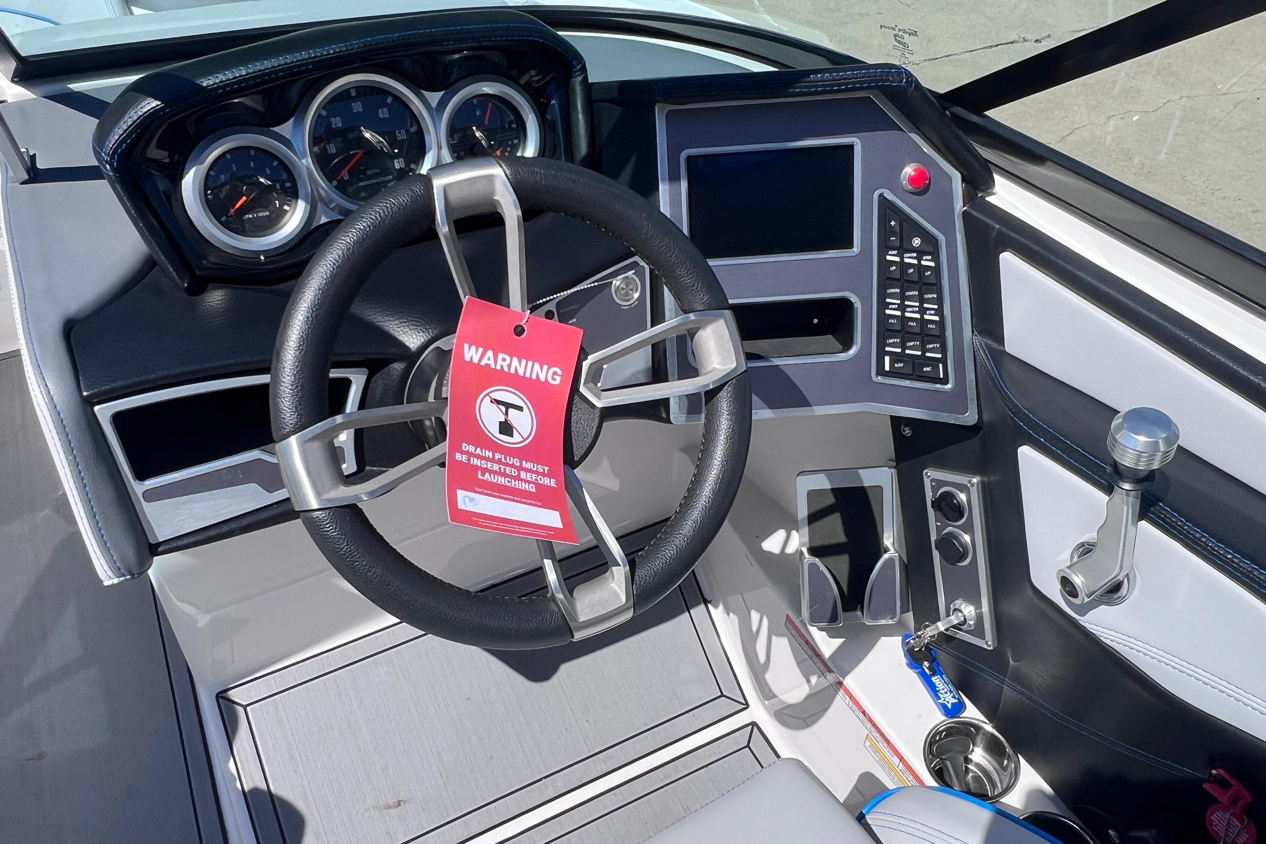 2021 MasterCraft XT23 boat dashboard with steering wheel, warning tag, and control panel.