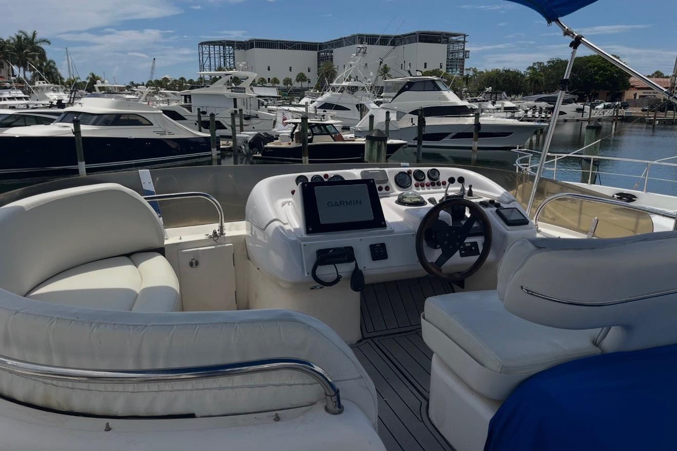 1999 Sealine F44 yacht cockpit with modern navigation system, docked in a marina.
