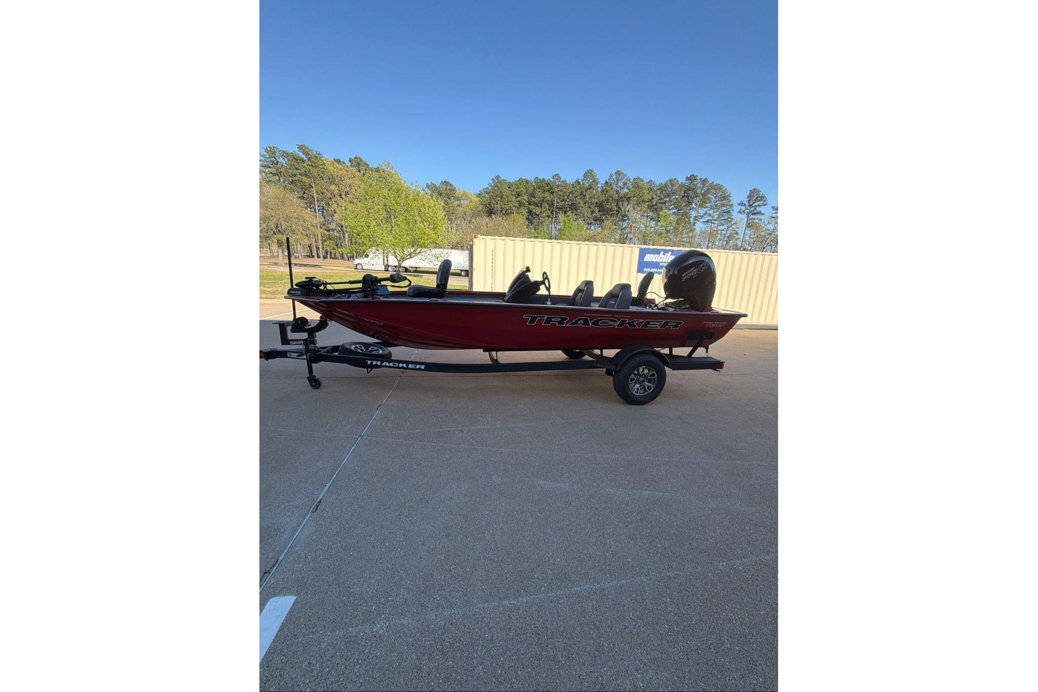 2026 Tracker Pro Team 195 boat on trailer, parked outdoors with trees in background.