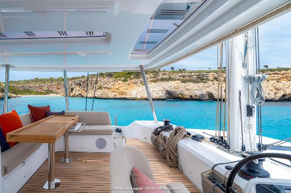 Luxurious Lagoon 55 yacht interior with ocean view, featuring elegant seating and wooden table, 2025 model.