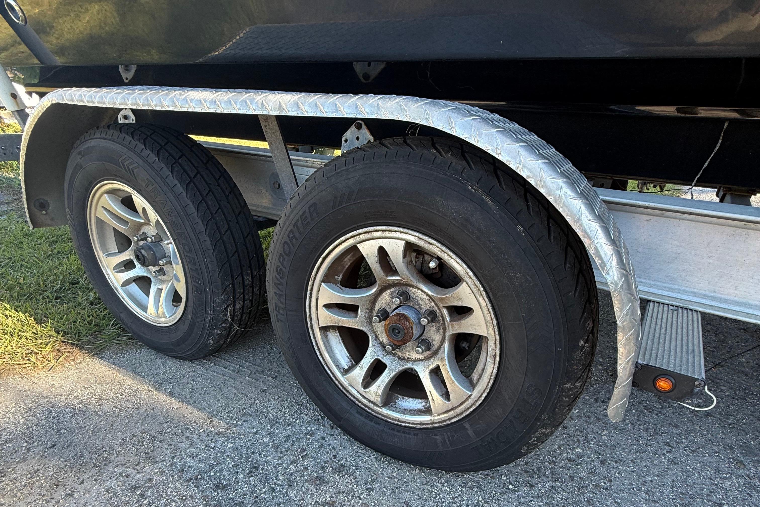 Trailer wheels of a 2021 Carolina Skiff 26 Ultra Elite boat on pavement.