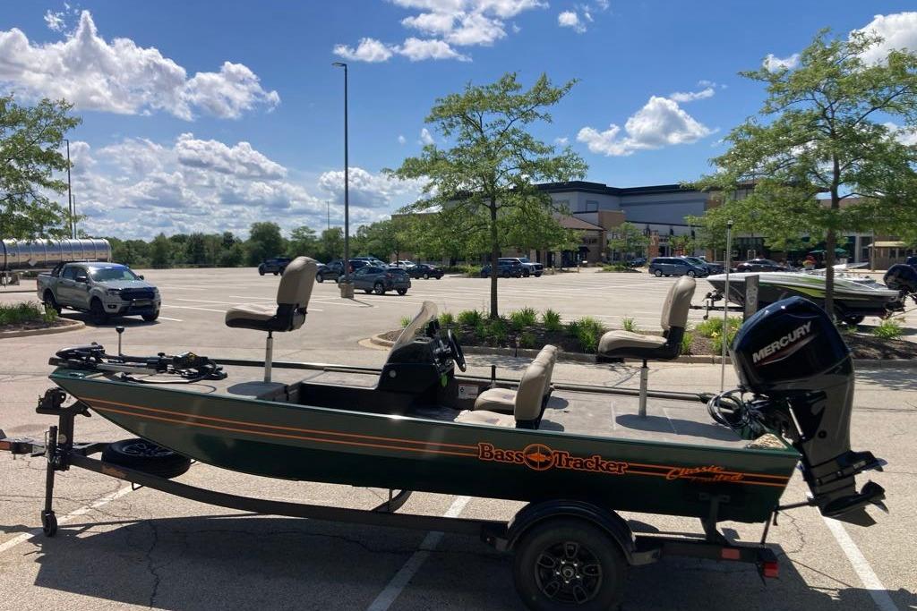 2026 Tracker Bass Tracker Classic Limited boat in parking lot under blue sky.