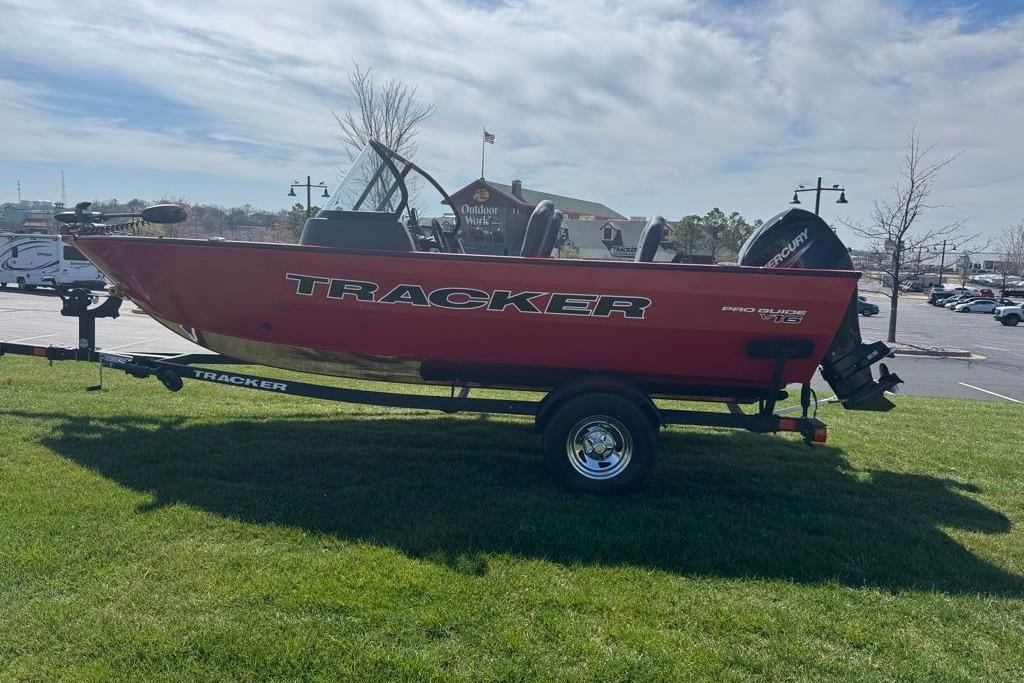 2026 Tracker Pro Guide V-16 WT boat on trailer, parked on grass under a cloudy sky.