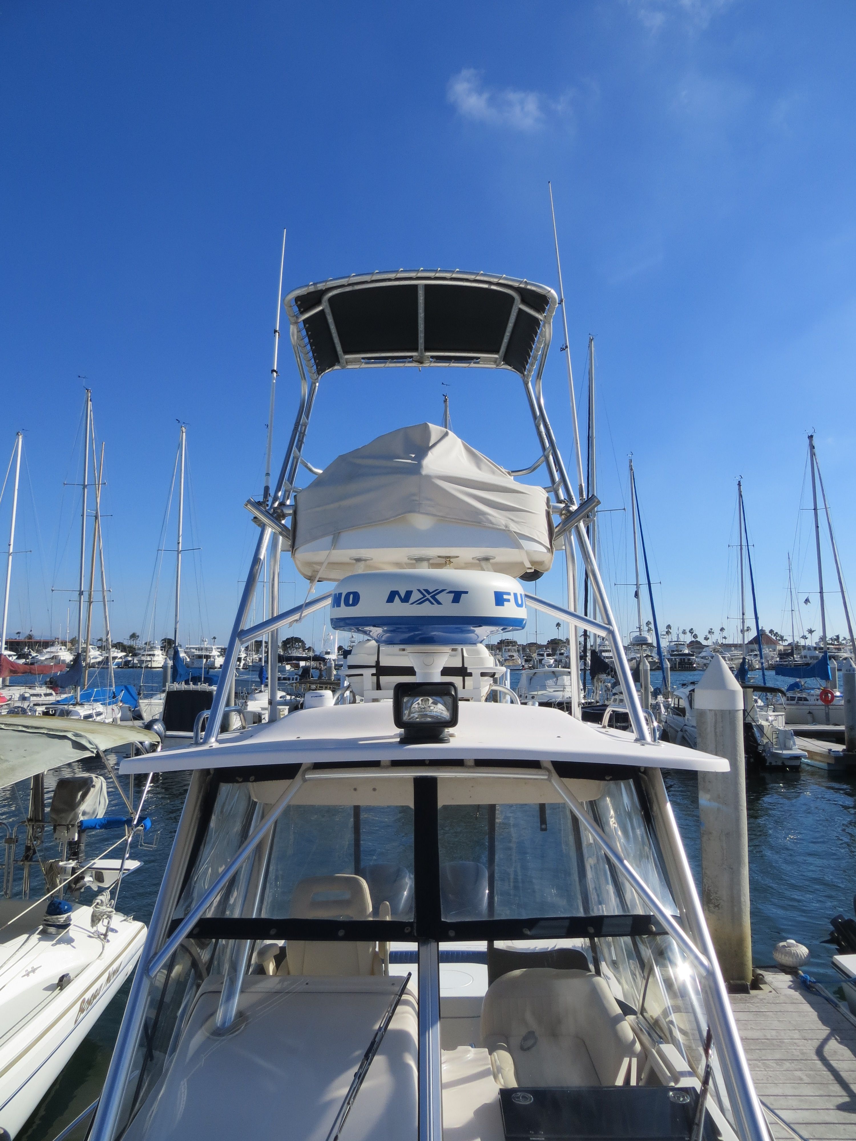 A Grady-White Sailfish 282 boat docked in a marina, surrounded by other boats and clear skies.