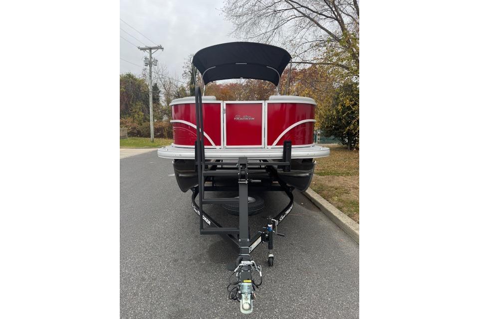 2026 Sun Tracker Party Barge 22 DLX pontoon boat on trailer, parked on a road.