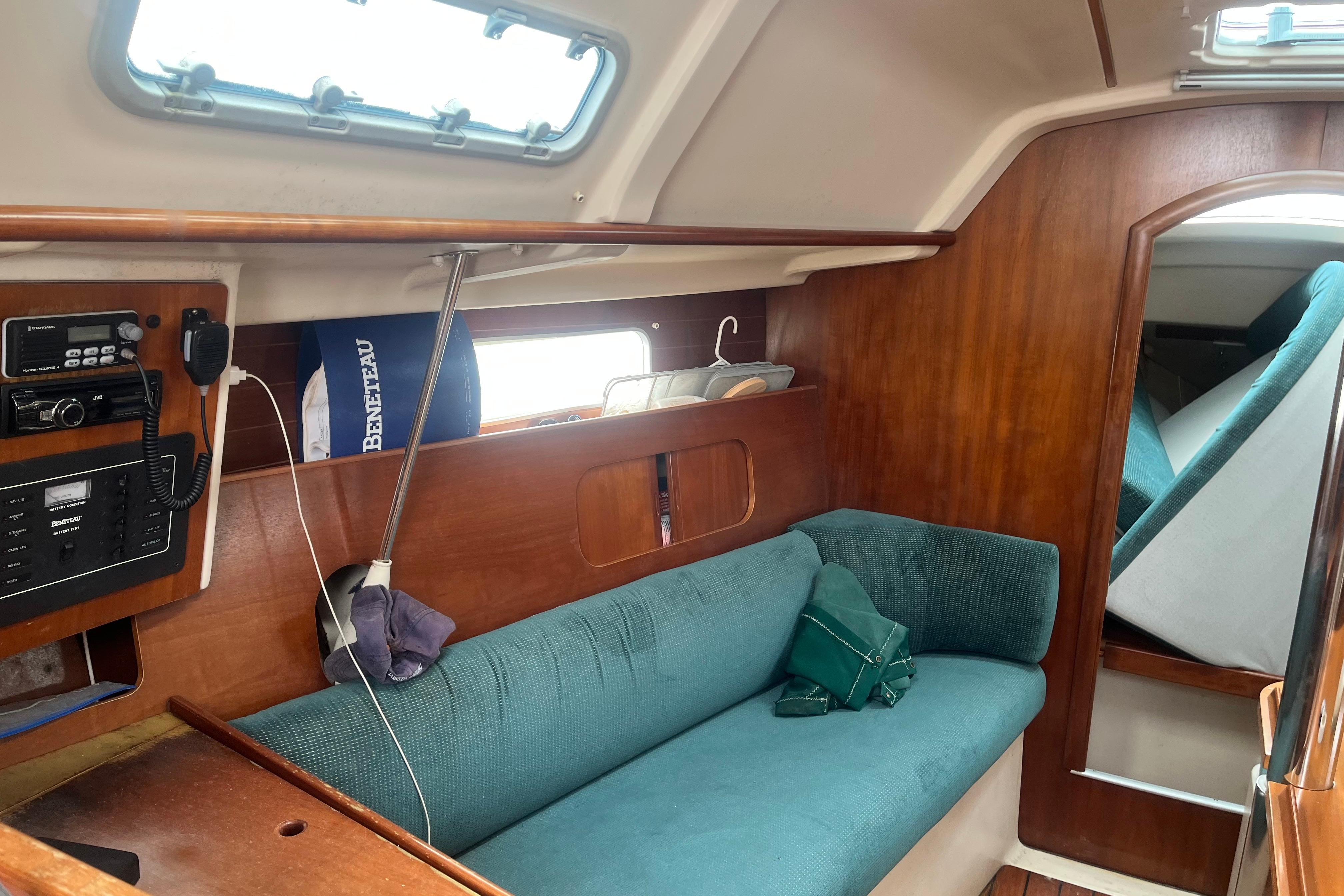 Interior of a 1999 Benneteau 321 Oceanis sailboat with teal seating and wooden paneling.