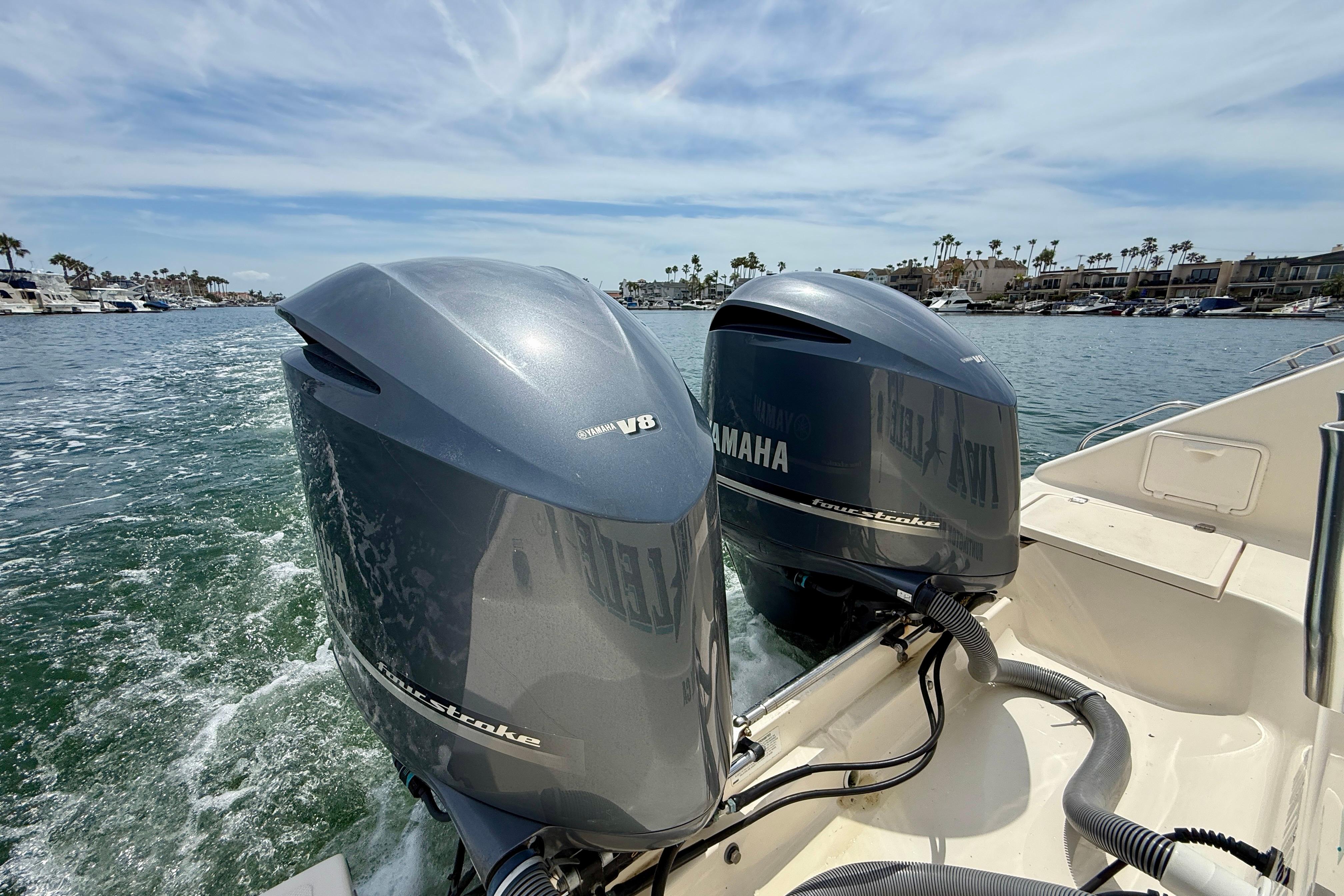 Twin Yamaha V8 engines on a 2012 Pursuit OS 345 Offshore boat in a marina.